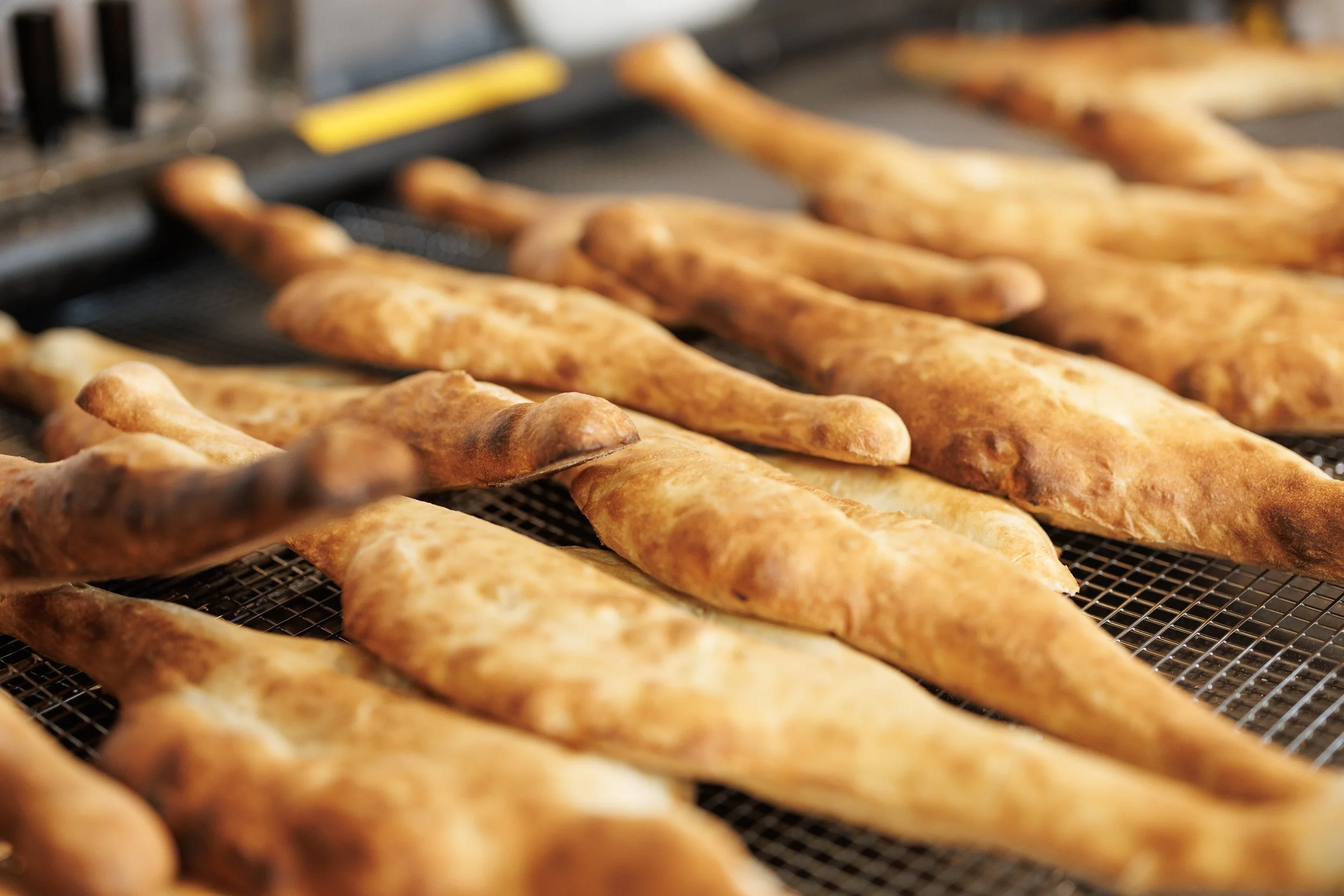 Several freshly baked breadsticks cooling on a wire rack.