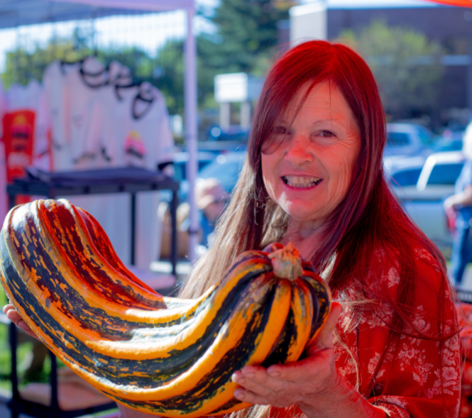 Wellspring Farm owner Treasa with a green and orange squash.