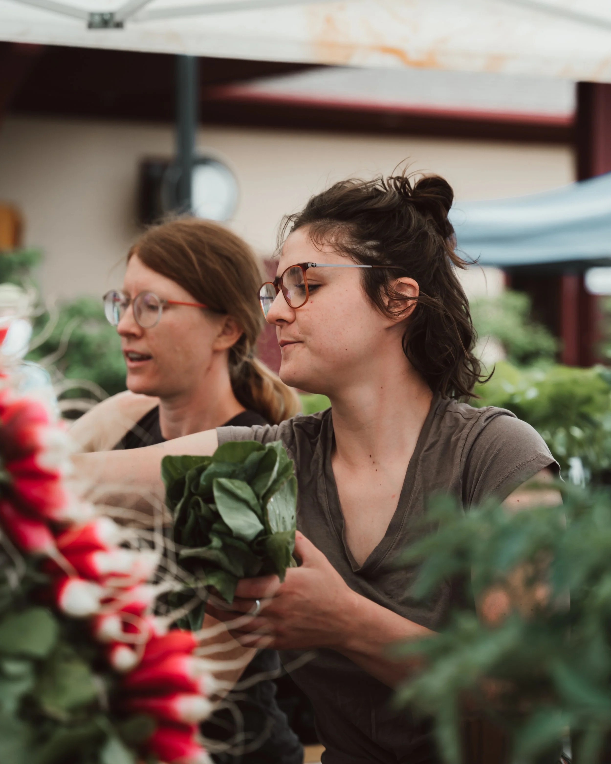 two women stocking a farm booth with produce
