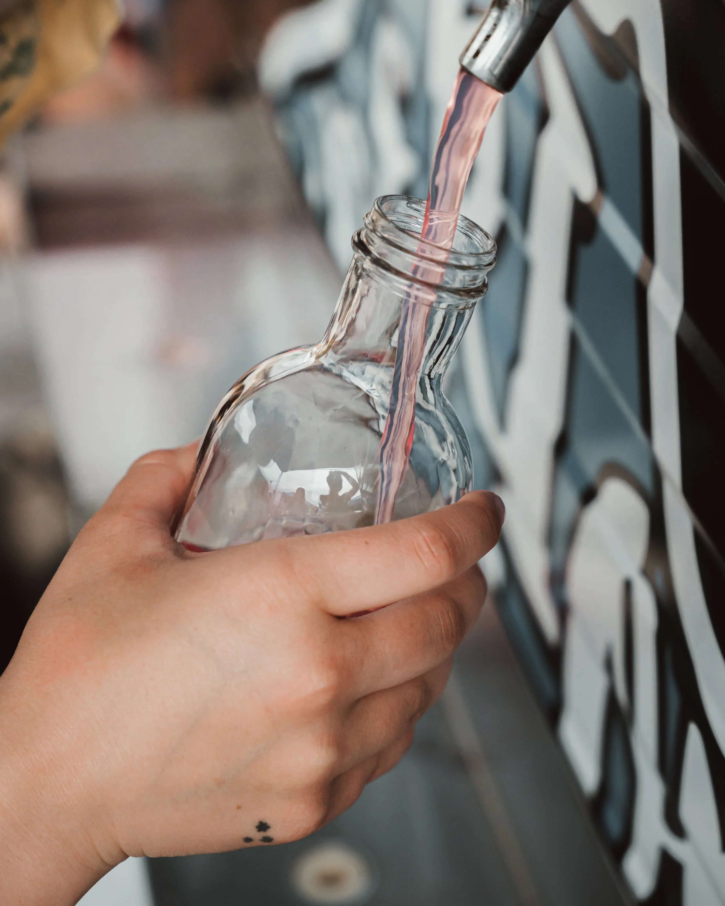 hand holding a gladd bottle and filling it with Kombucha