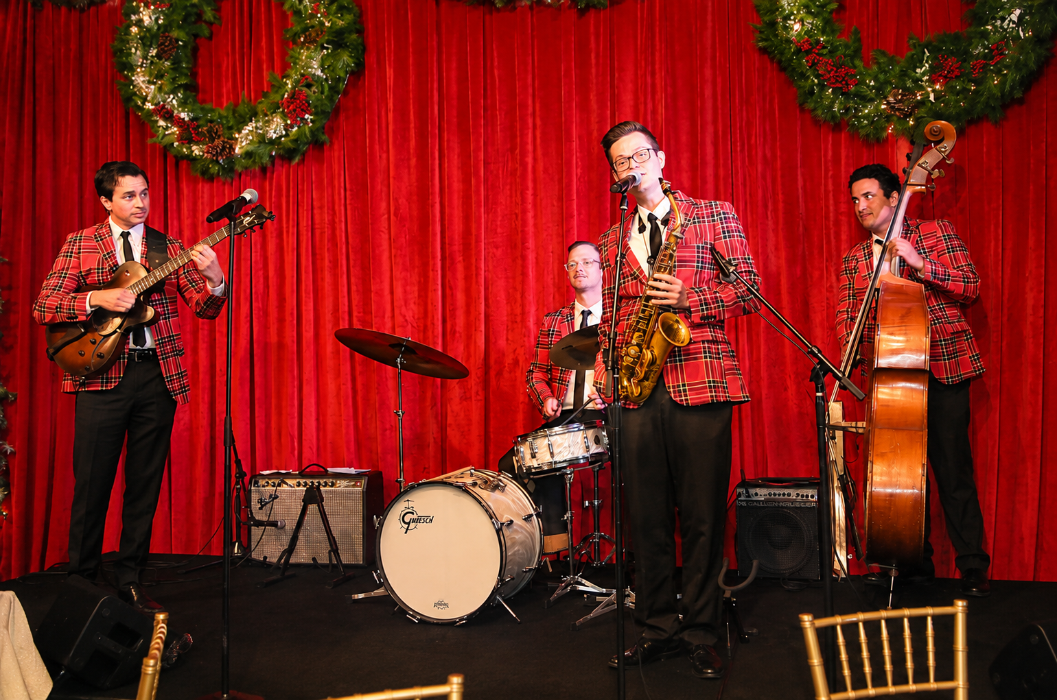 Live 4 piece band musicians performing Holiday Christmas music on a festive holiday stage.