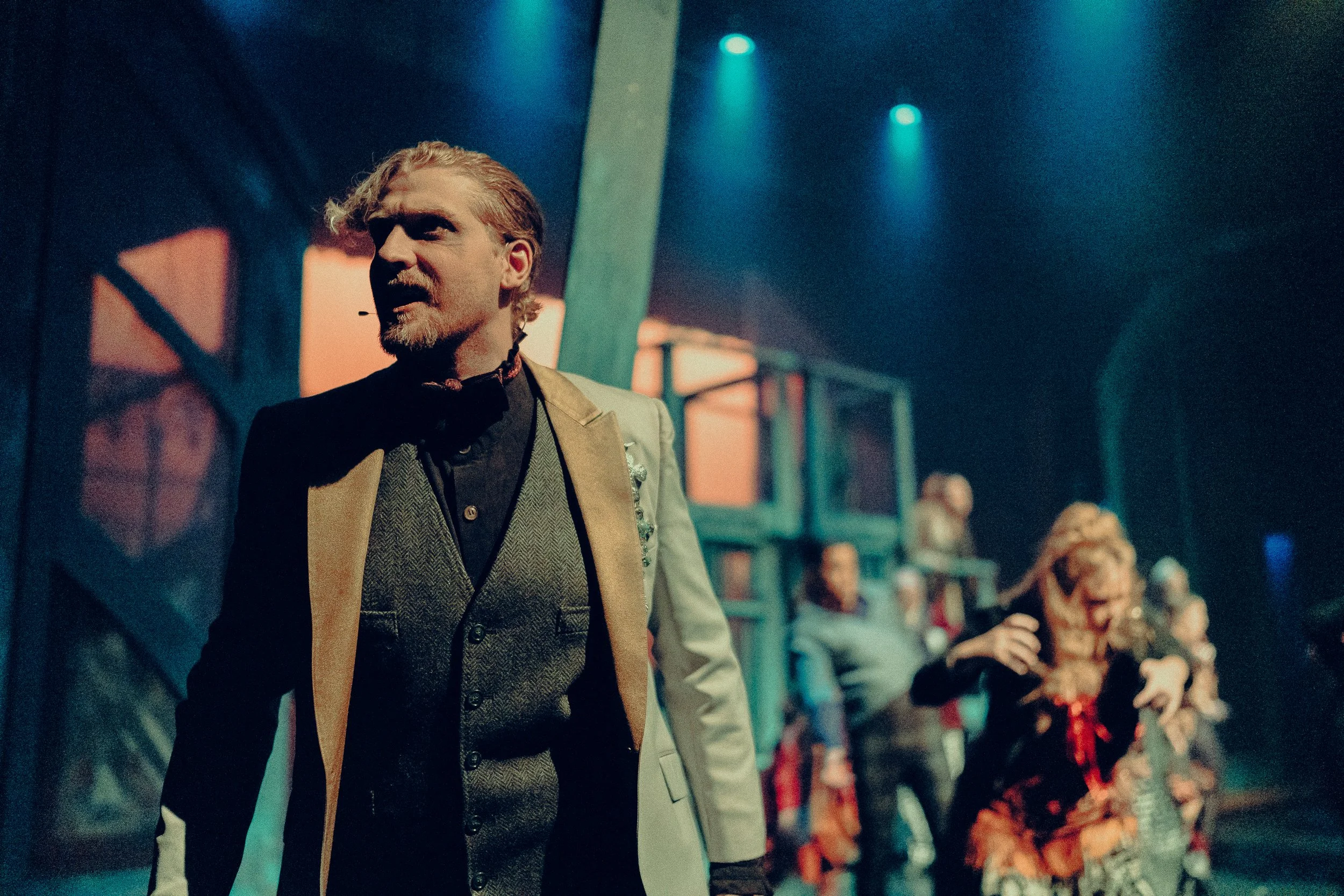 Theater production with a man in a suit performing on stage.