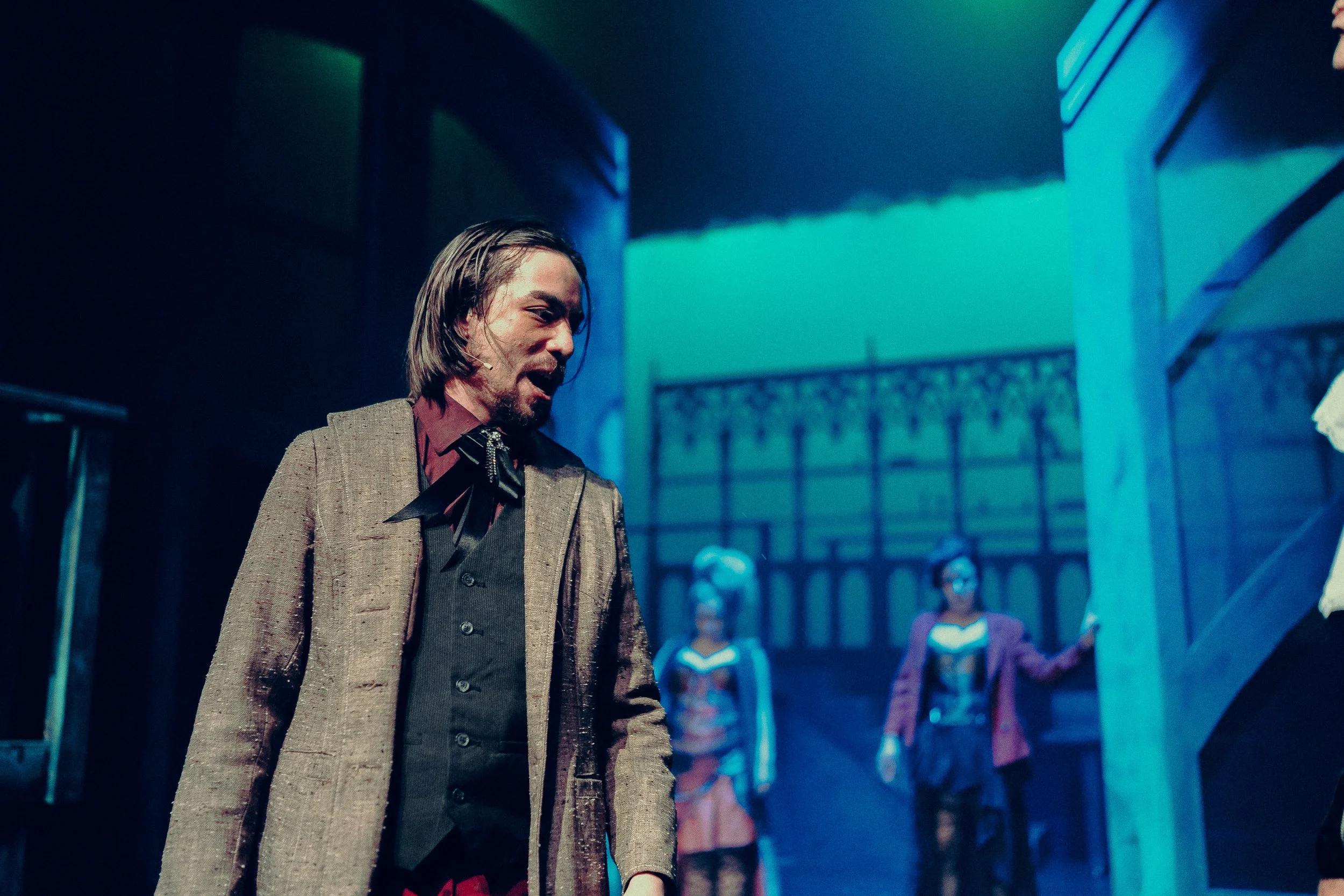 Actor in period costume performing on stage with dramatic lighting and set design