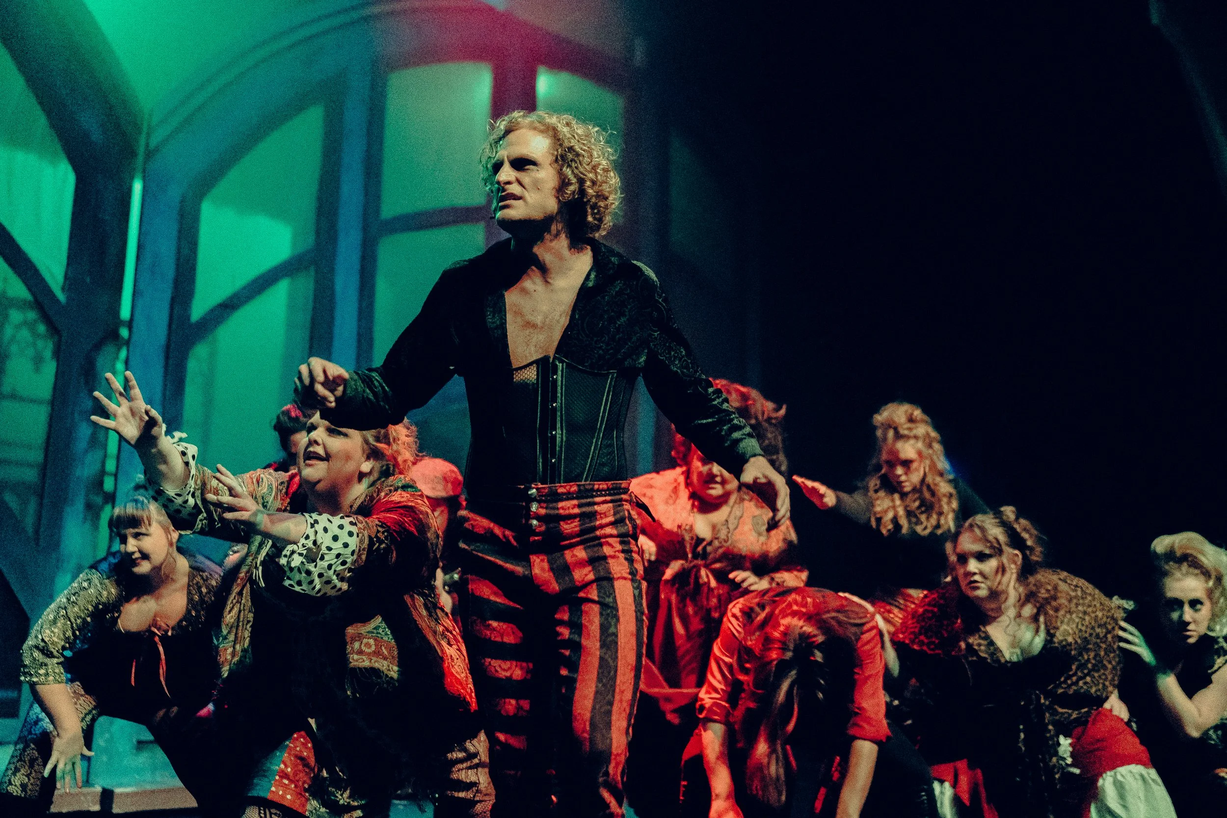 Actors performing a dramatic scene on stage with colorful costumes and expressive gestures.