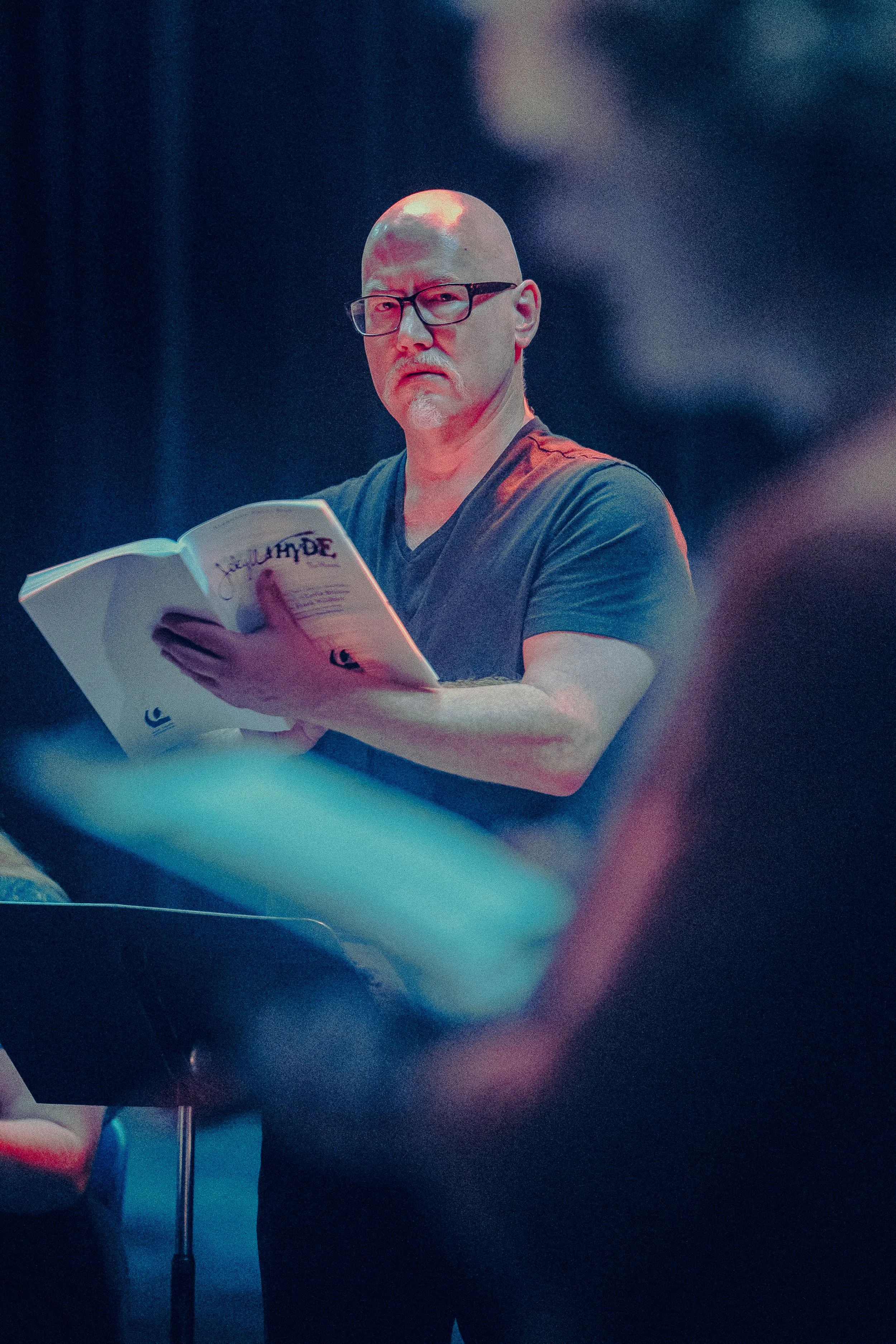A person reading a script, focusing intently, in a dimly lit setting.