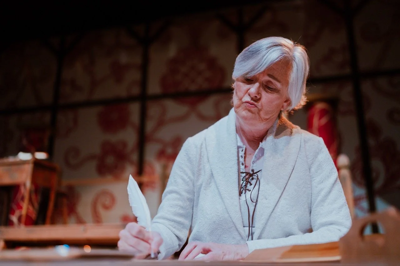 Elderly woman writing with a quill pen