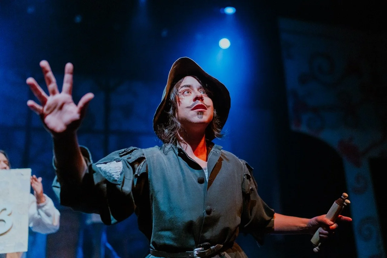 Actor in costume performing on stage with dramatic lighting.