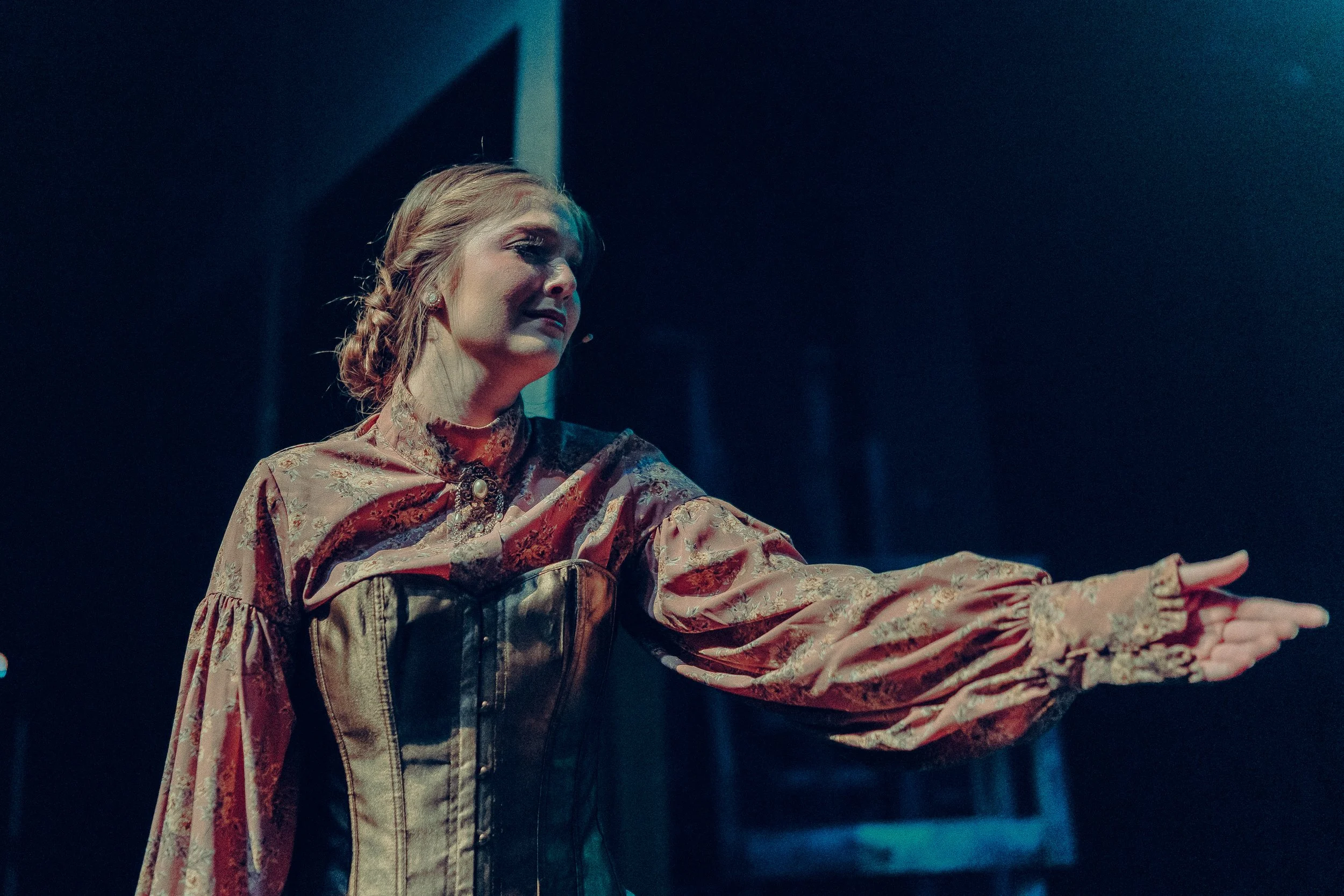 Woman in vintage costume performing on stage with dramatic gesture