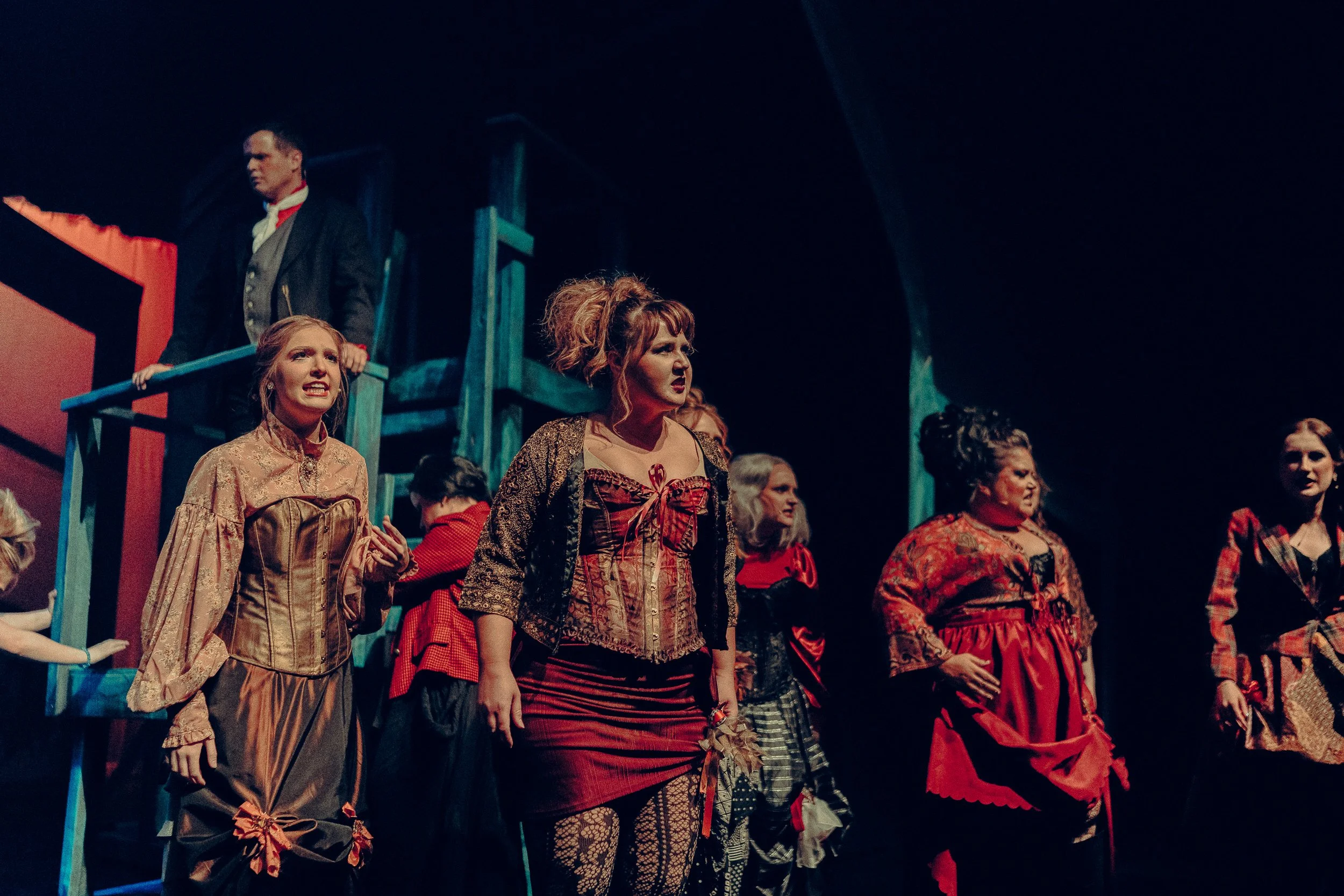 Theatrical performance with actors in period costumes on stage.