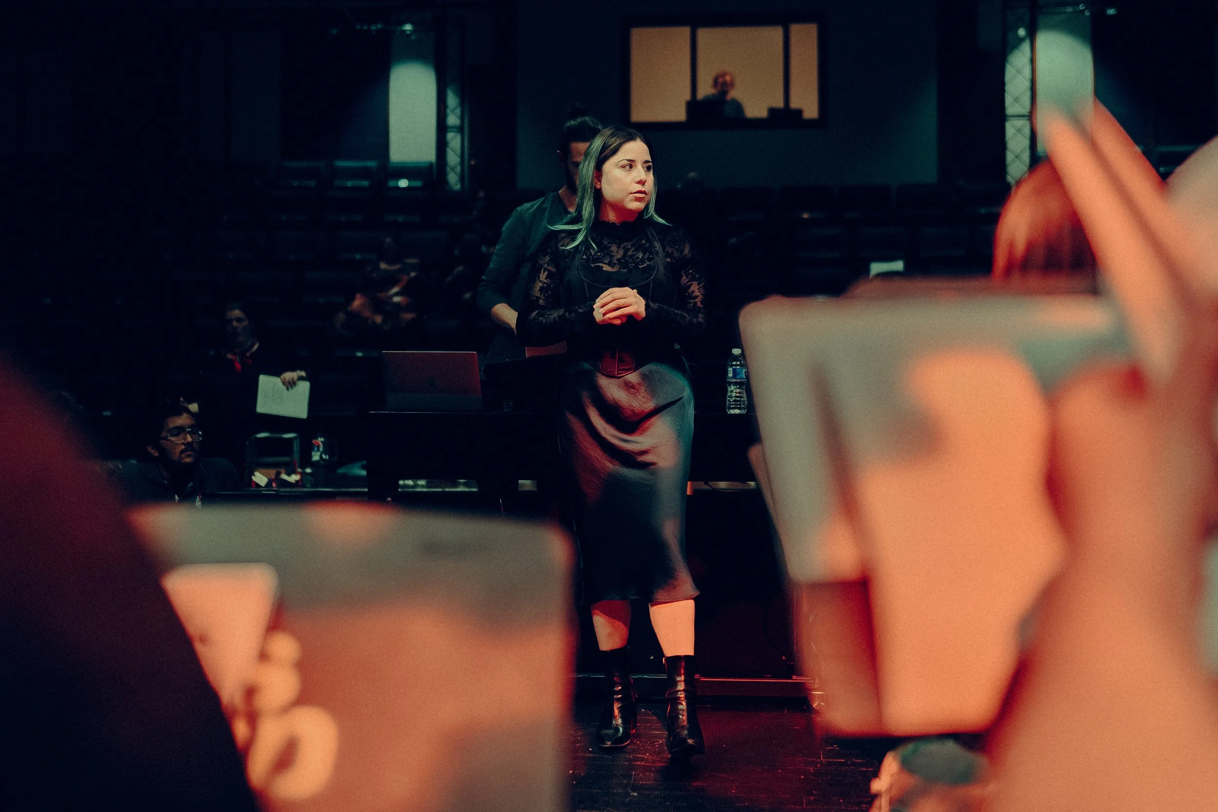 Woman standing on stage during rehearsal with audience in background