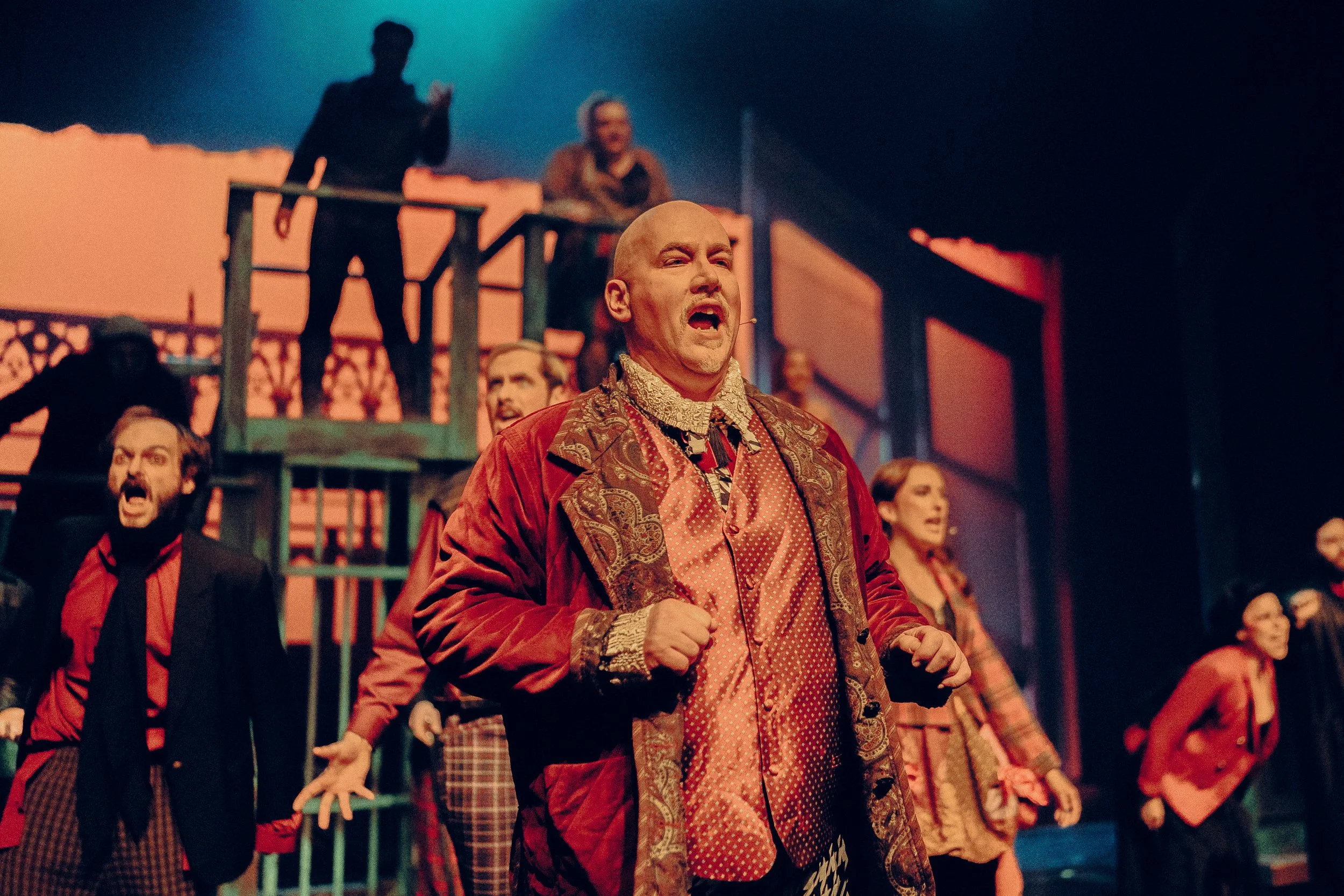 Theater actors performing on stage in costume with dramatic expressions.