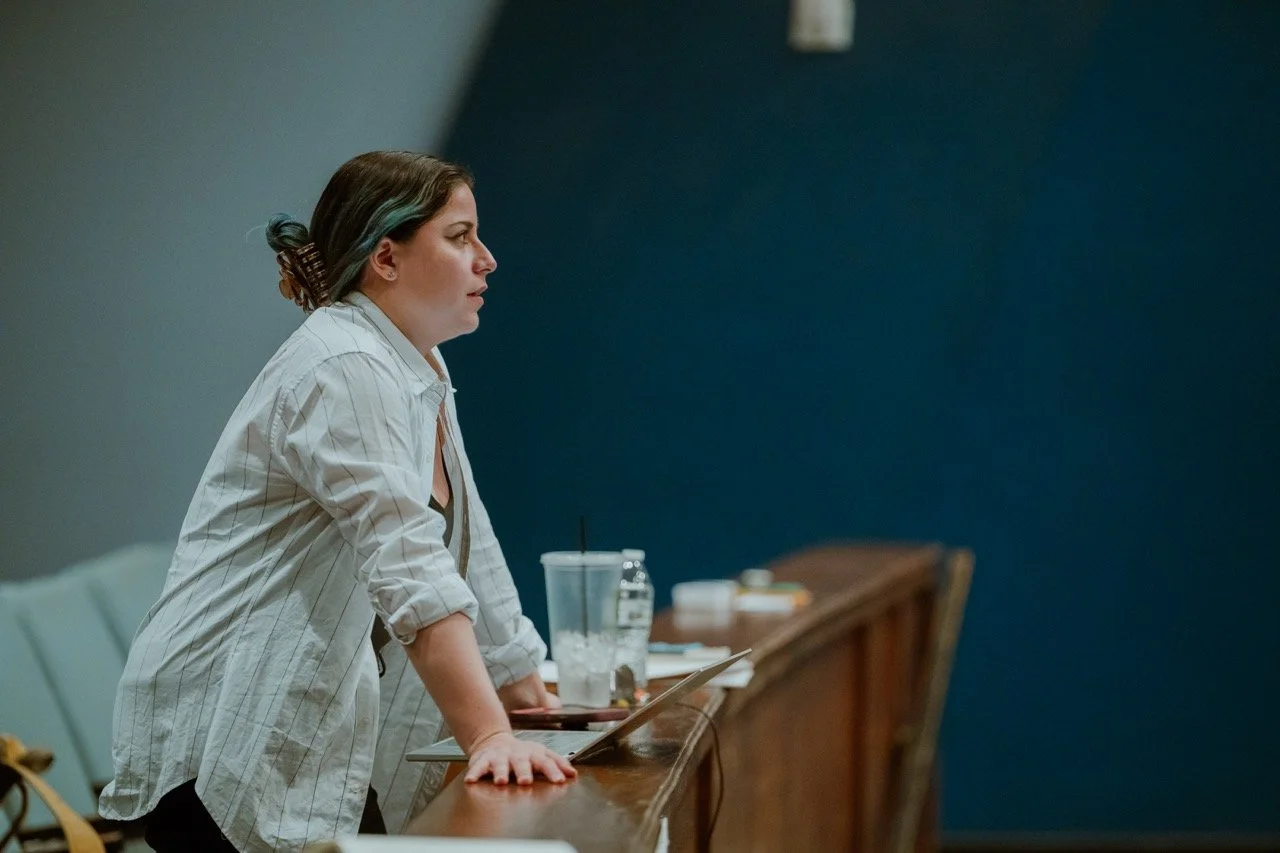 Person in white shirt leaning on table in lecture hall, focused on listening