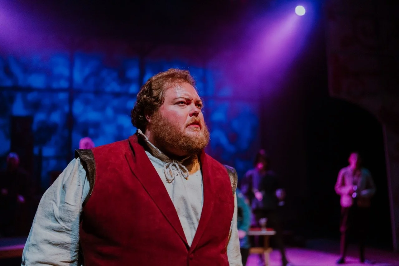 Actor in a theater production with dramatic lighting.