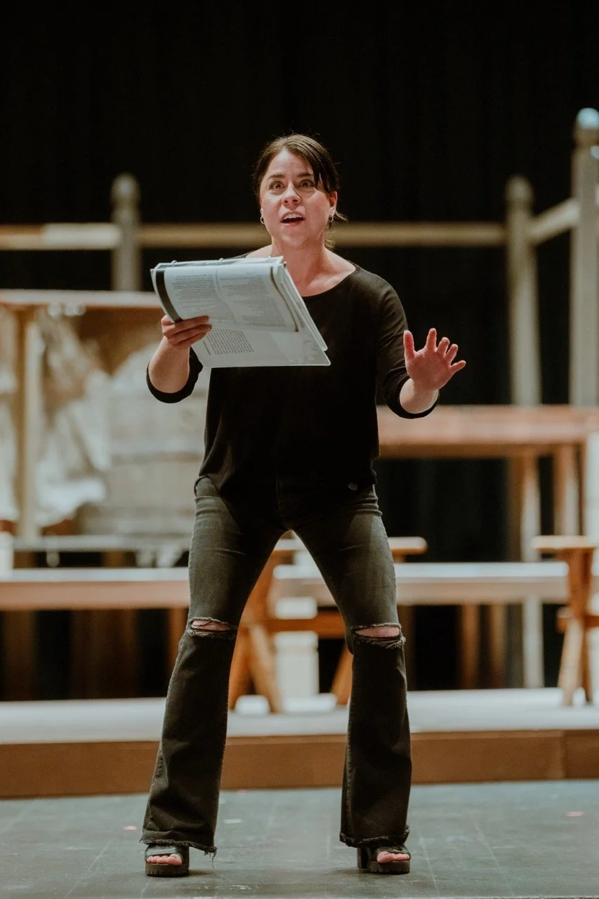 Woman rehearsing on stage, holding script.