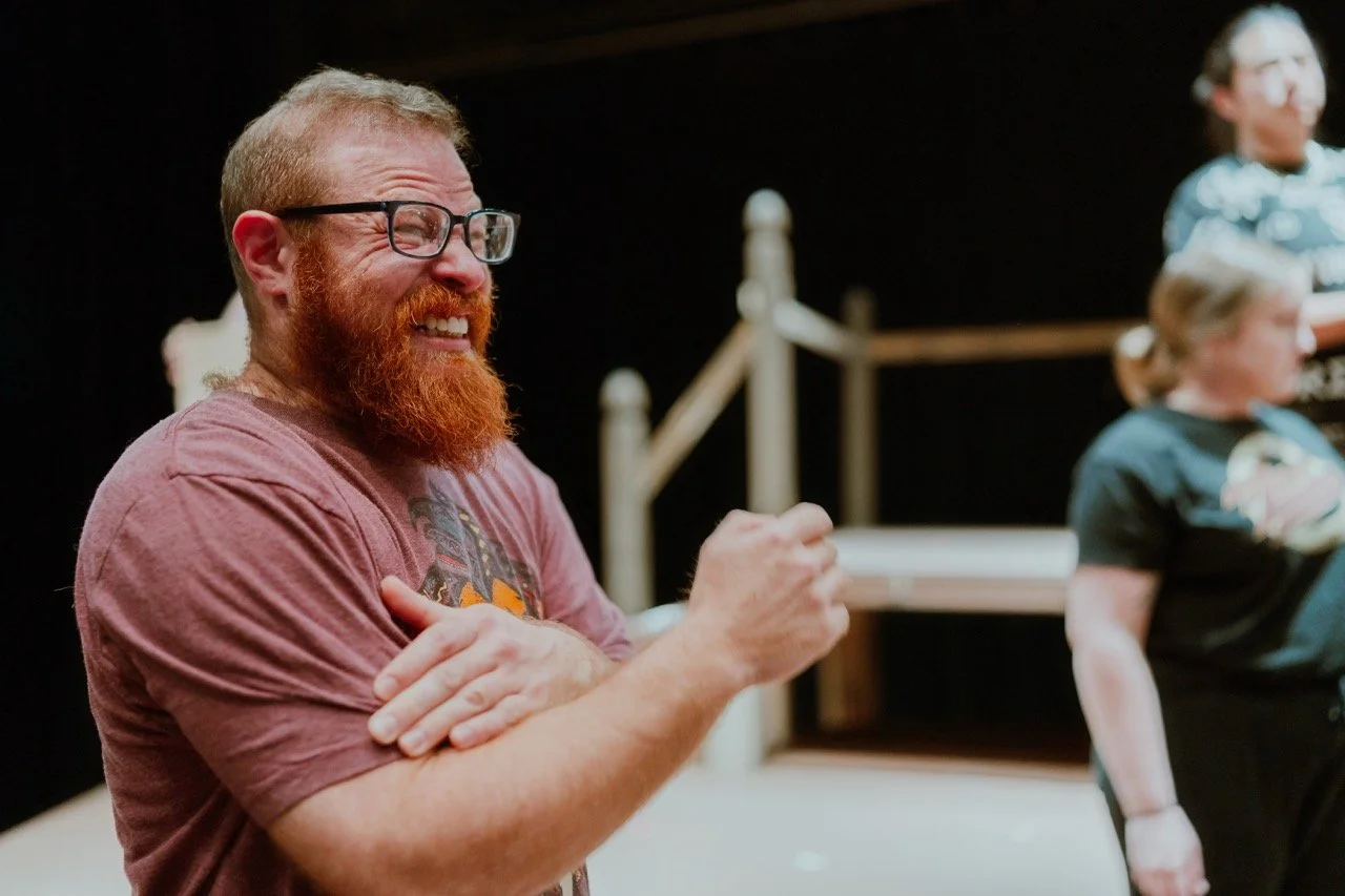 Man with red beard and glasses smiling in a casual setting