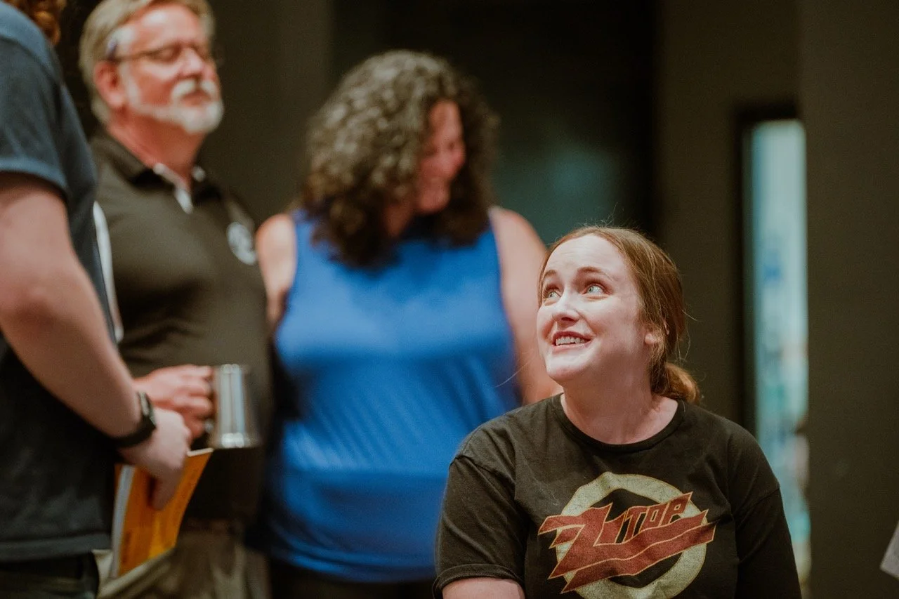 Group of people socializing indoors, one person smiling and looking up.