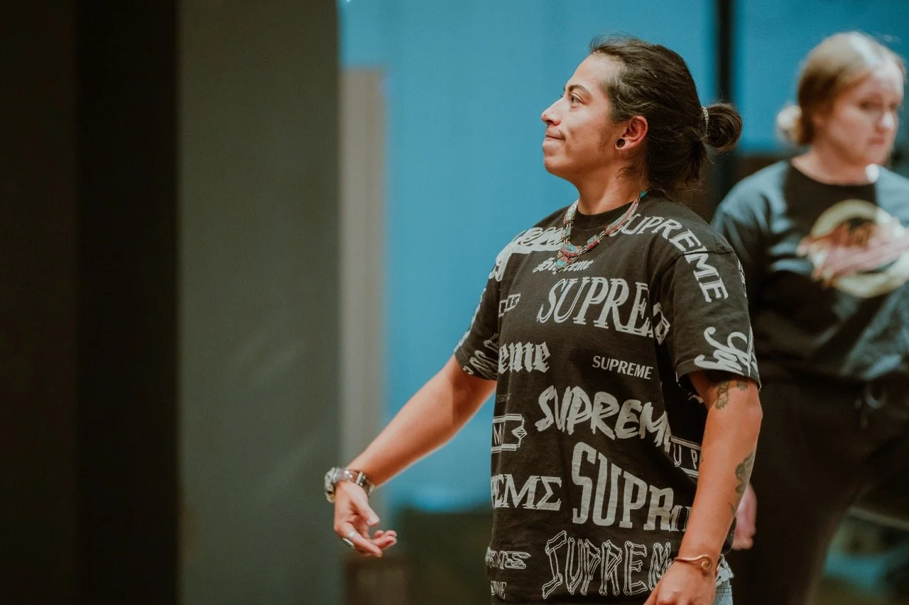 Person wearing a black t-shirt with 'Supreme' logo in a rehearsal setting.