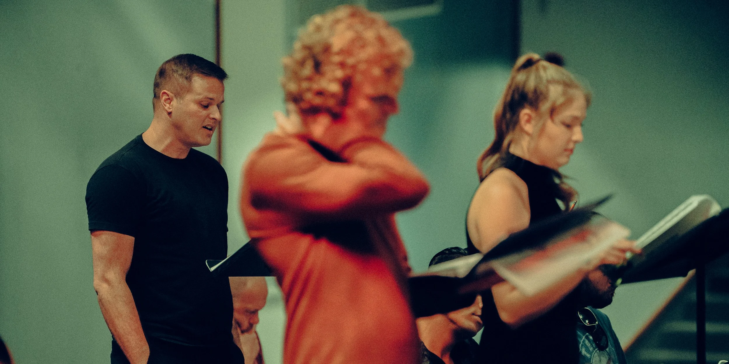 Group of people singing from hymnals while practicing choral music