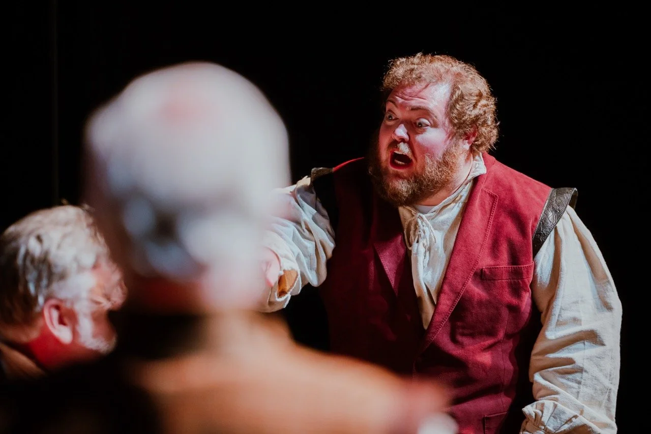 Actor passionately performing on stage in historical costume.