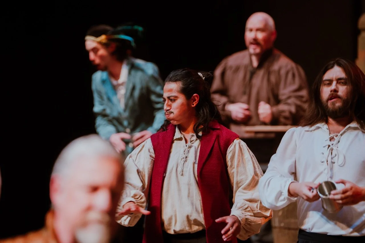 Actors on stage in historical costumes, performing a play