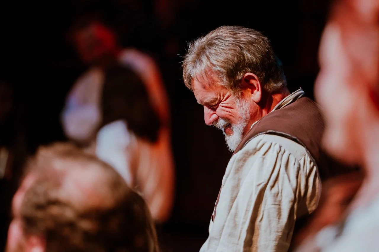 Elderly man smiling in a warmly lit room.