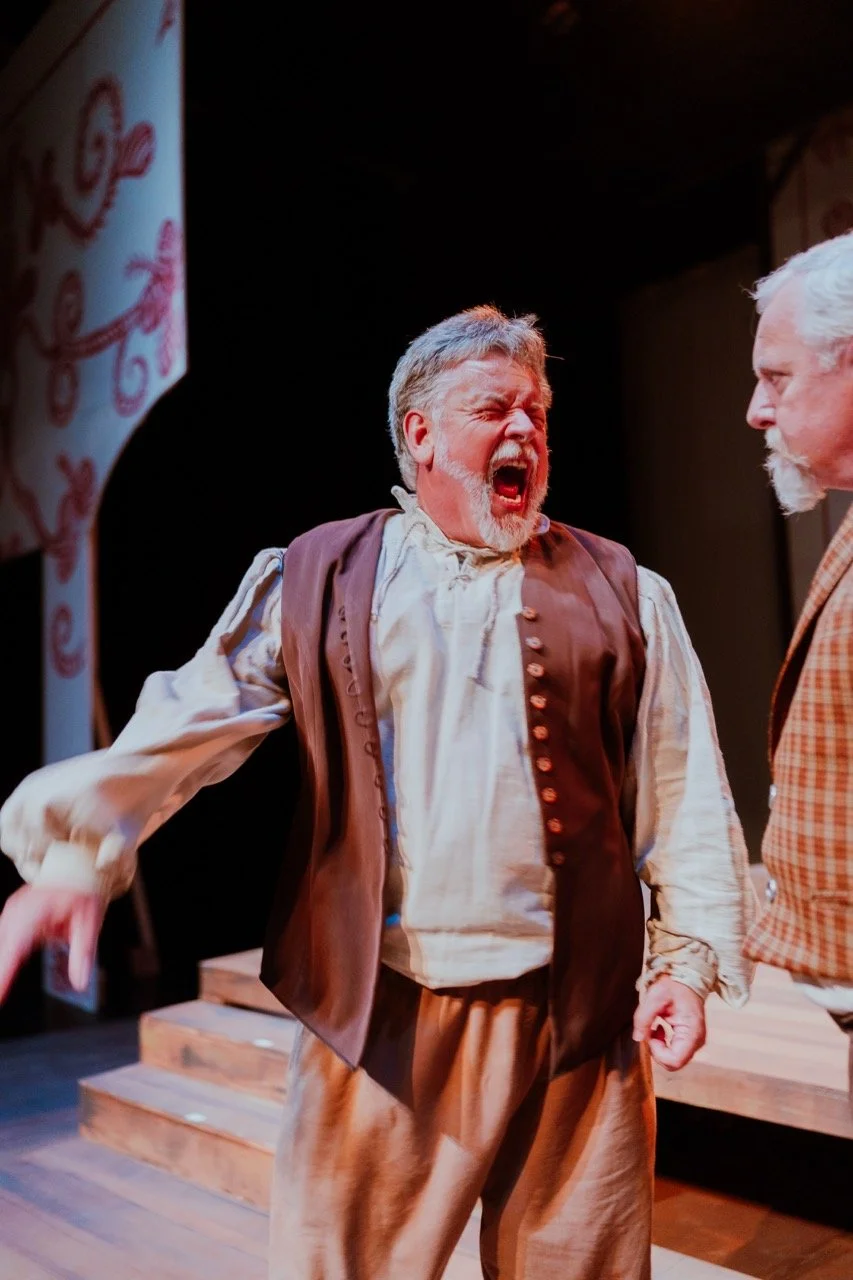 Two men in period costumes on stage, one yelling passionately during a performance.