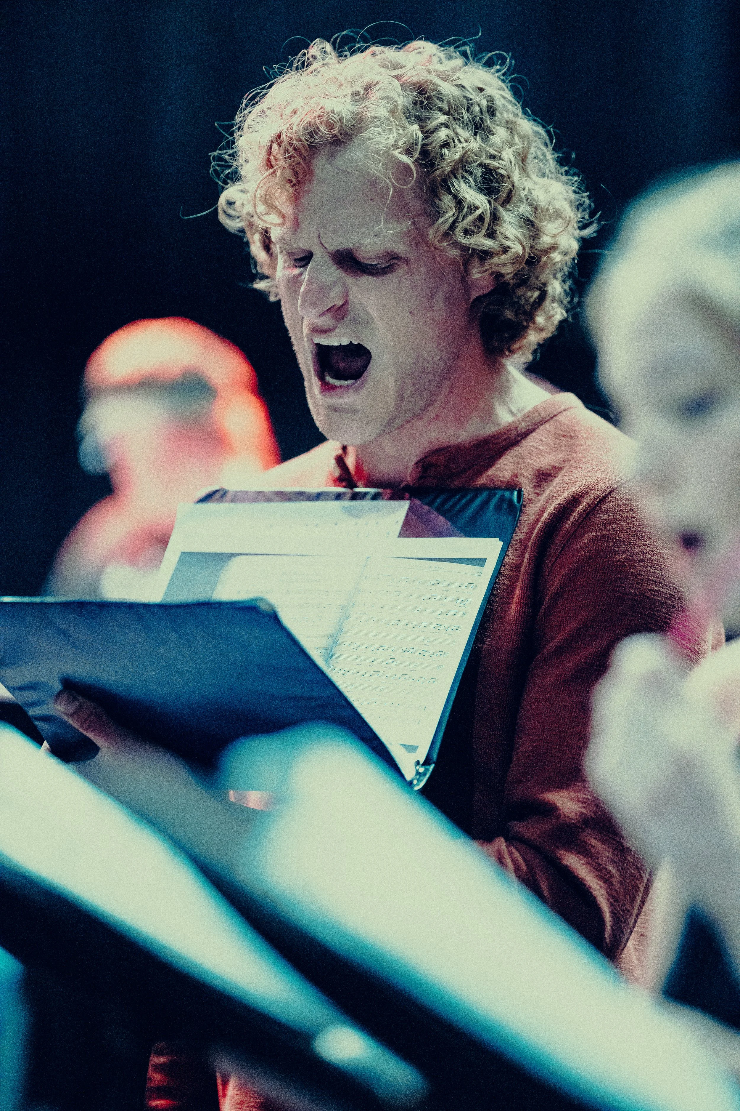 Man passionately singing from sheet music during rehearsal