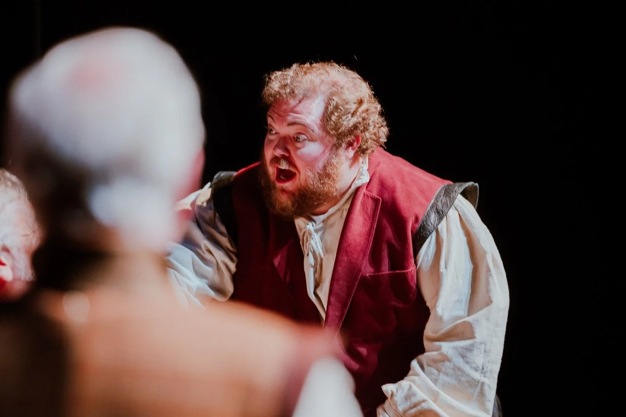 Actor in Renaissance-style costume with expressive facial expression on stage