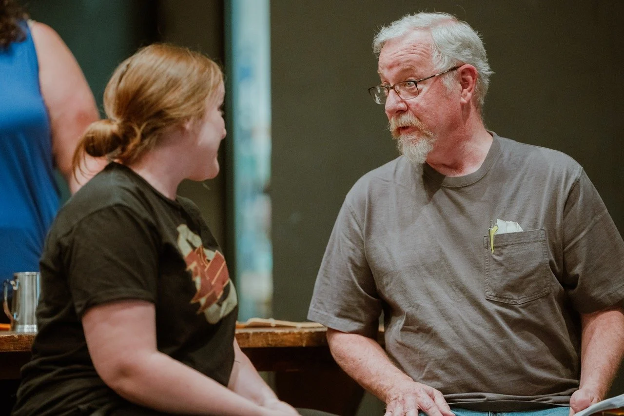 A young woman and an older man sitting and having a conversation indoors.