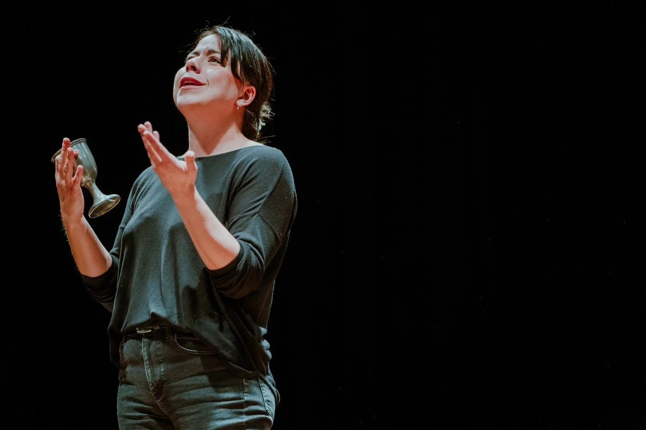 Person performing on stage holding a metal goblet