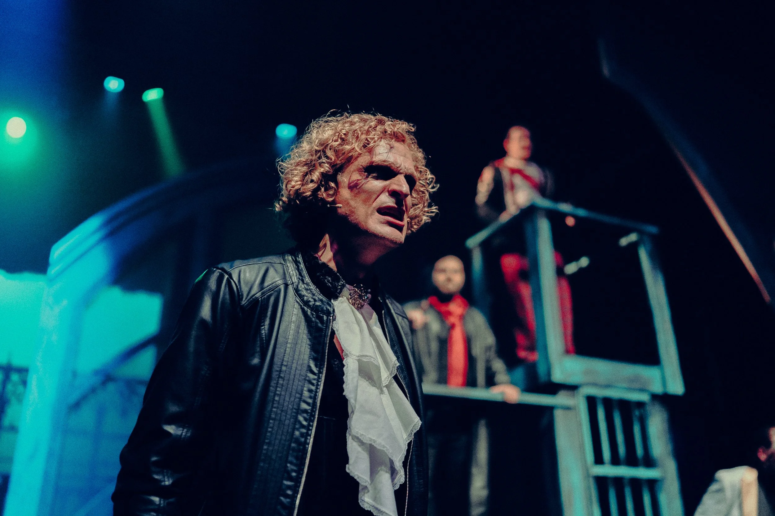 Theatrical performance with actors in dramatic costumes and expressive lighting on stage.