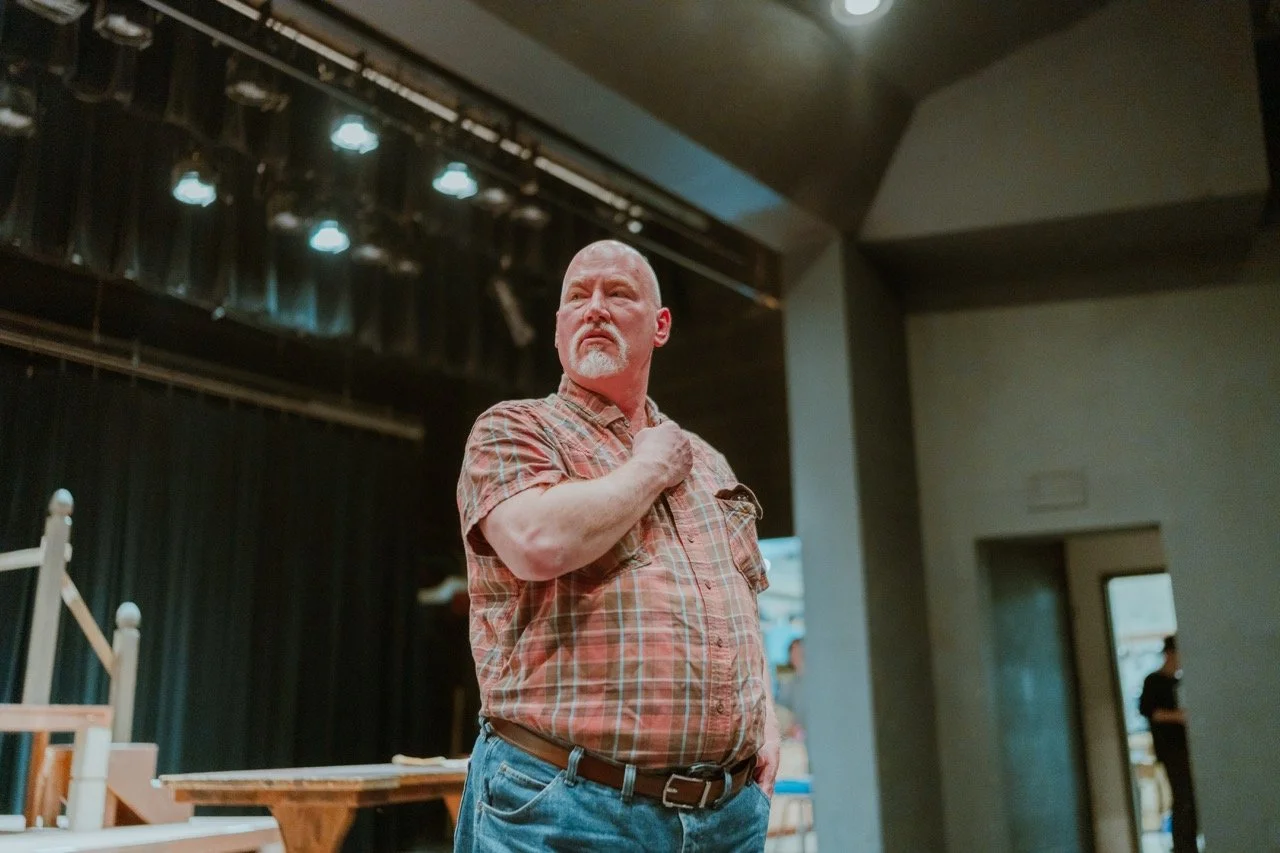 Man in plaid shirt standing on stage under lights