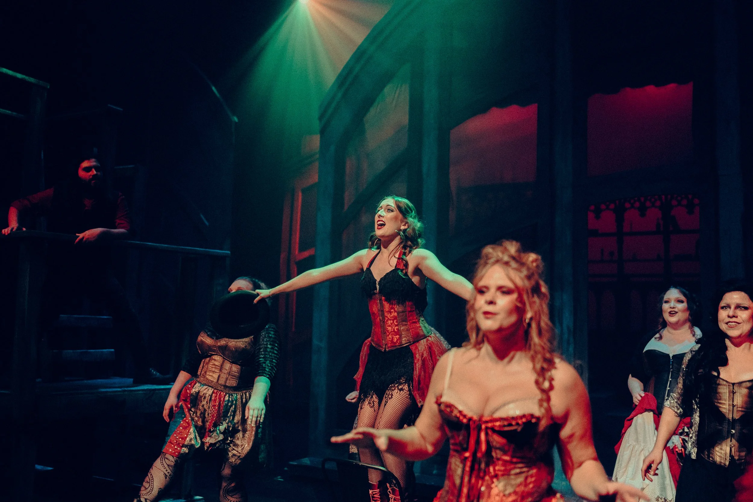 Stage performance with actors in vintage costumes, dramatic lighting, theatrical setting.