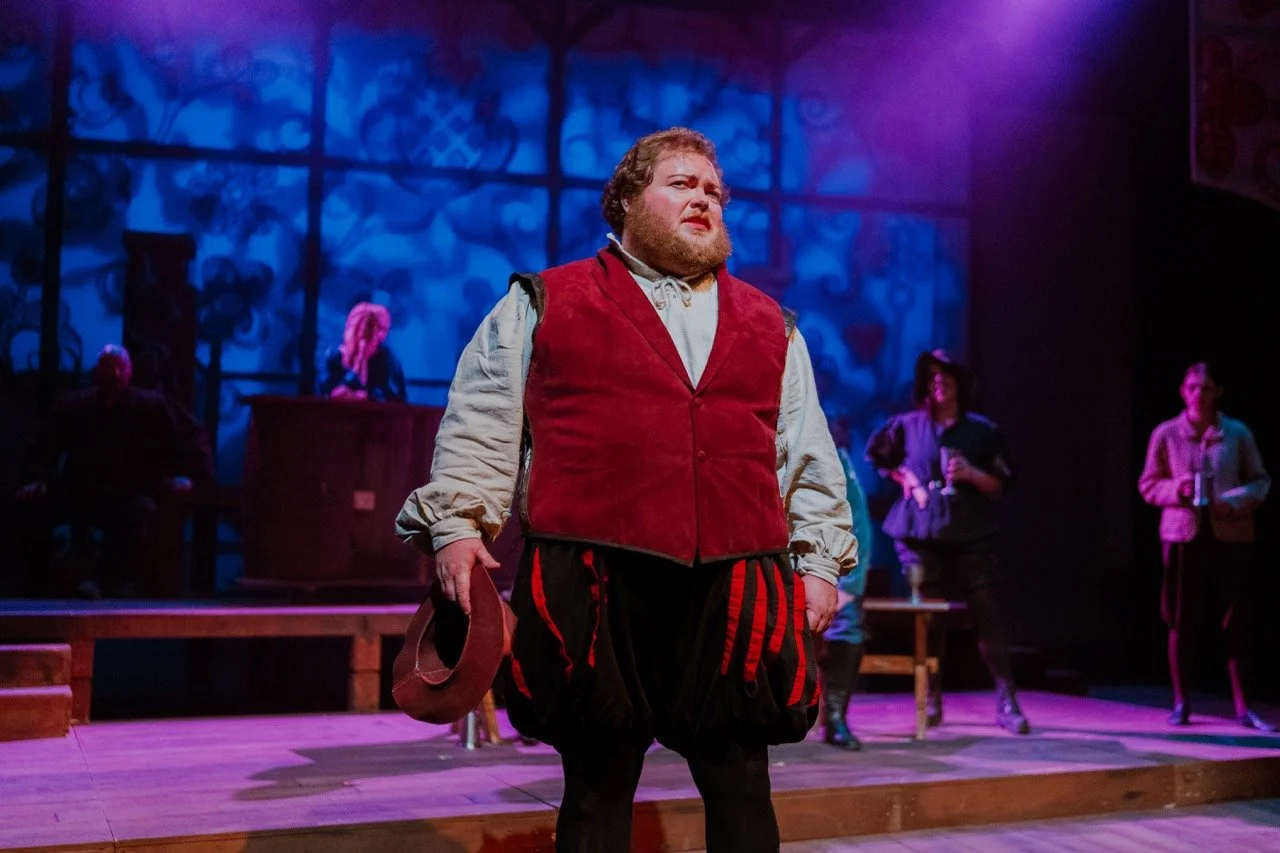 Theatrical performance with a man in historical costume on stage.