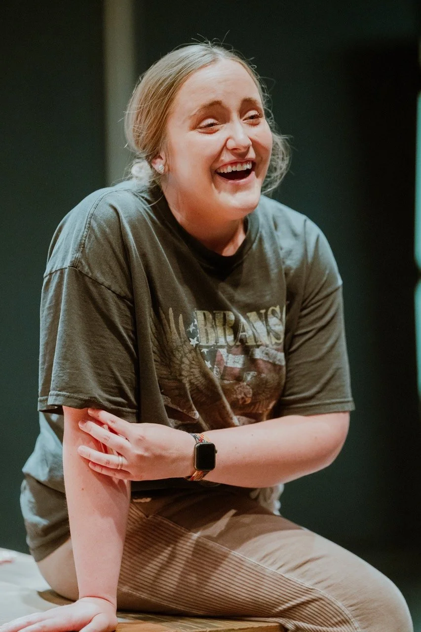 Person laughing and sitting, wearing a dark t-shirt and smartwatch.