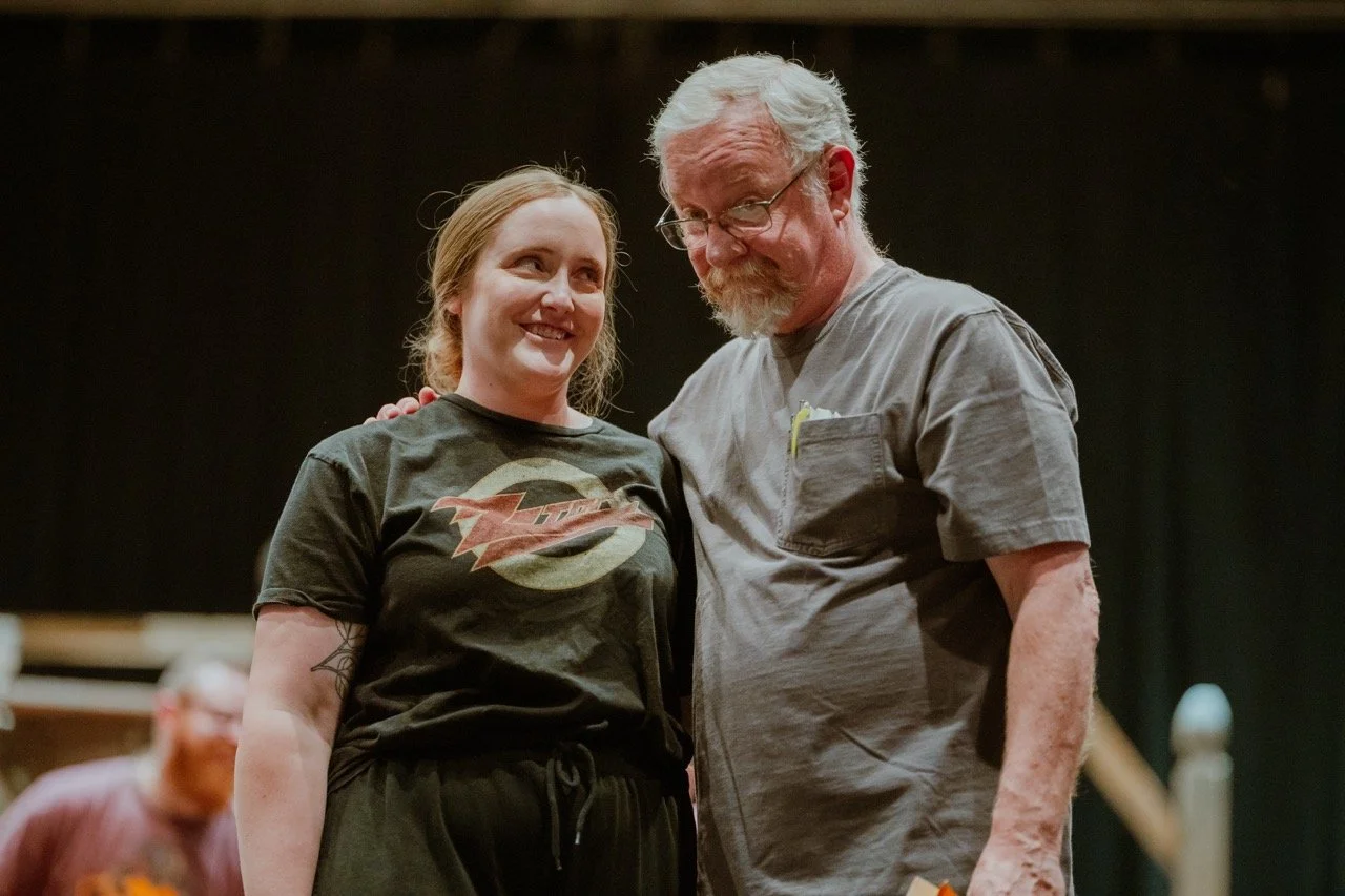 Two people smiling with arms around each other