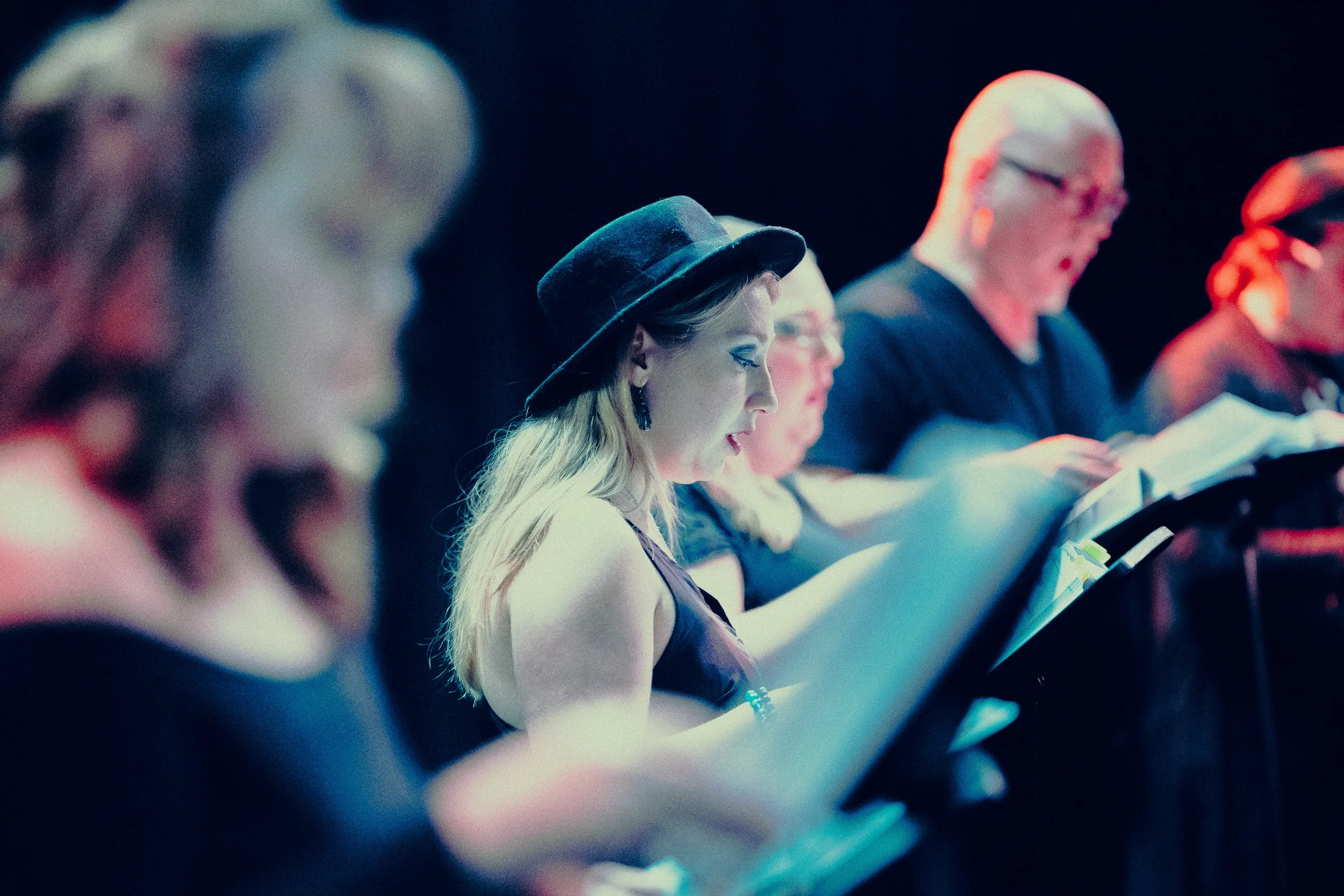 Group of people singing from sheets on stage