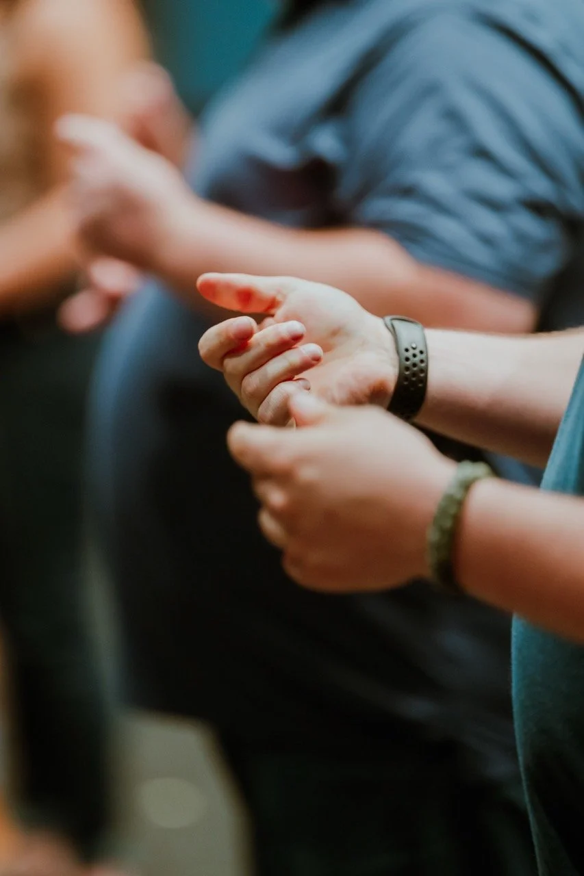 Close-up of people holding a red liquid drop, focus on hands.
