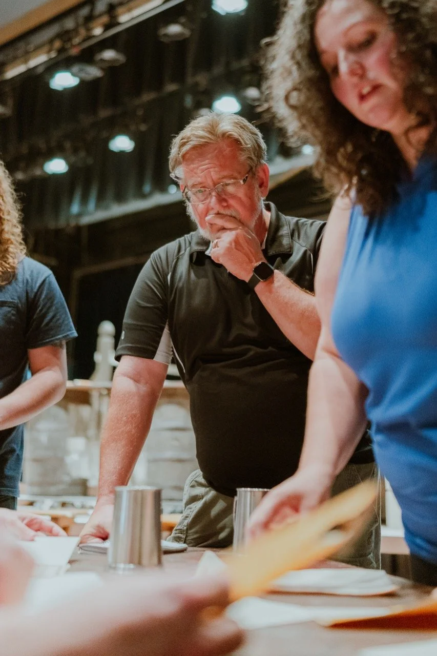 People gathered around a table reviewing papers in a theater setting.