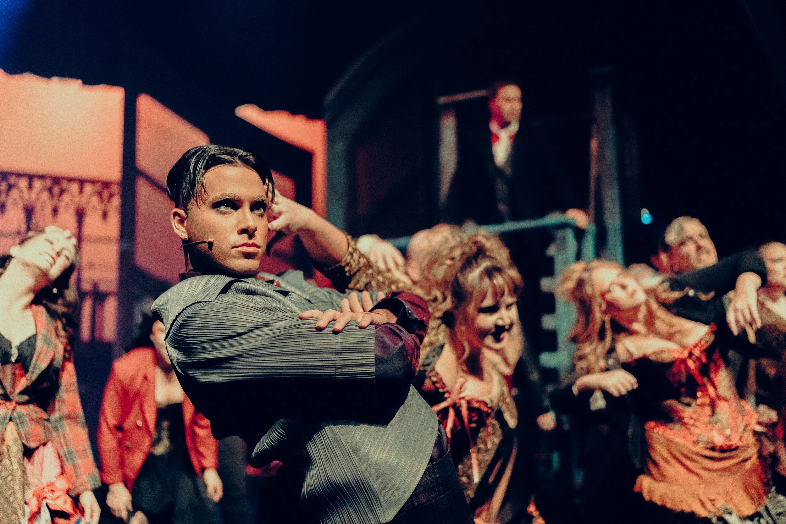 Theatrical performance with dancers in vibrant, period-style costumes on stage.