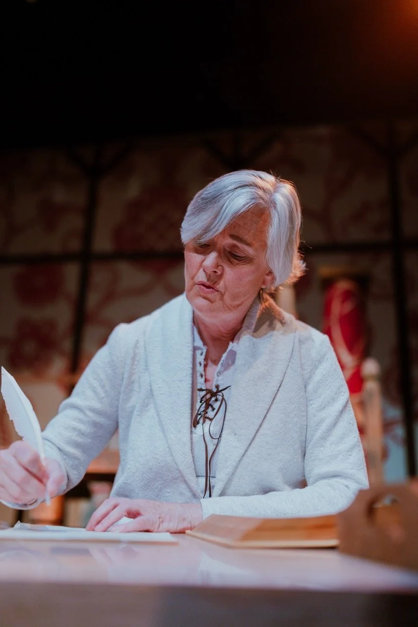 Elderly person writing with a quill pen