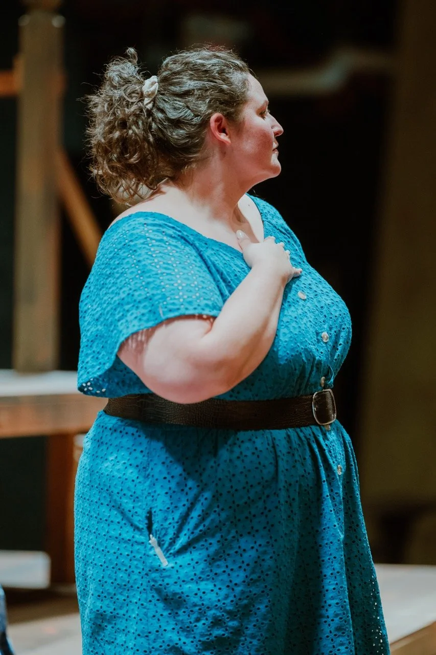 Person wearing a blue dress with a black belt, standing indoors.