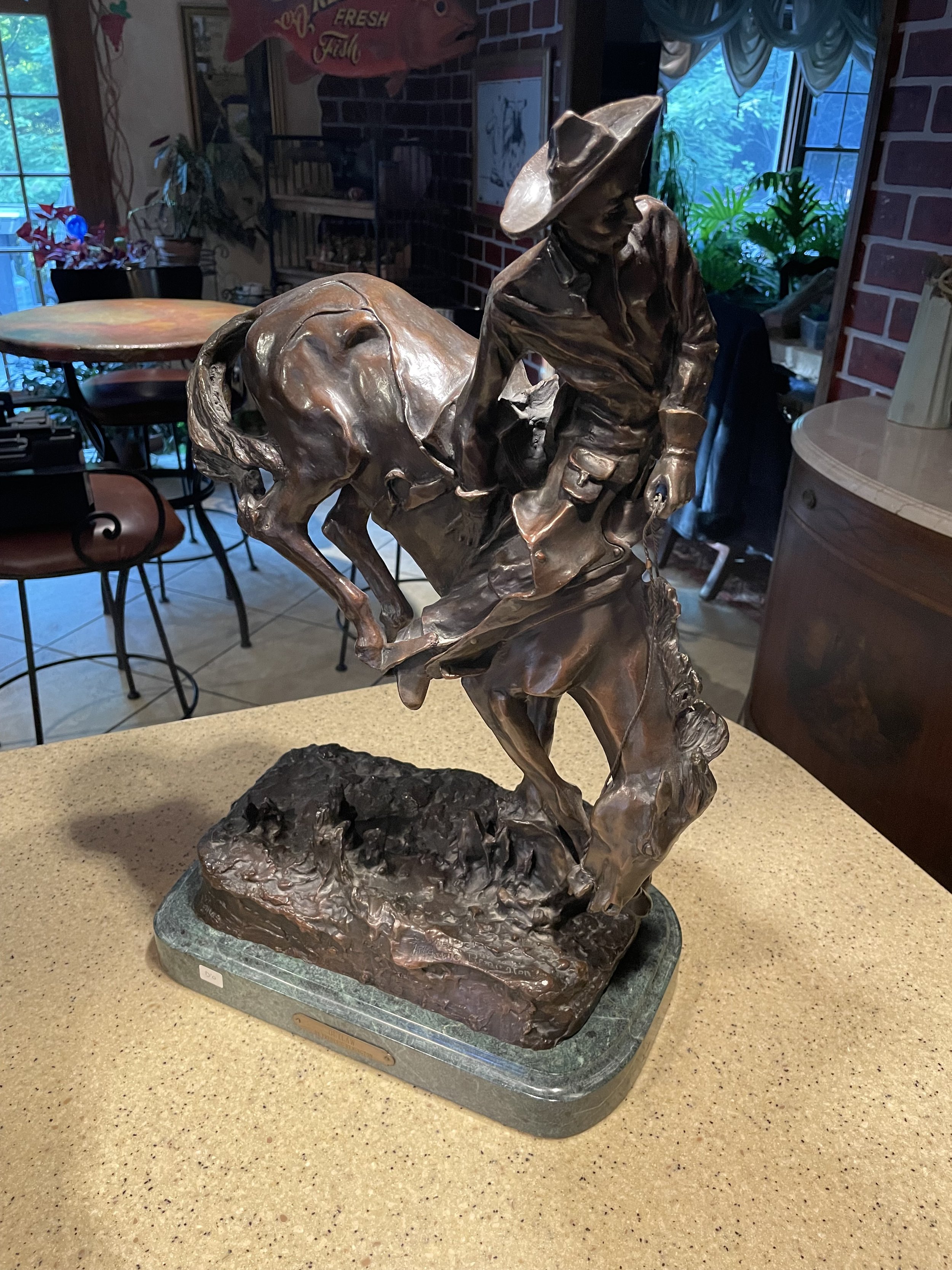 Bronze sculpture of "The Outlaw" by Frederic Remington, securely mounted on a green marble base