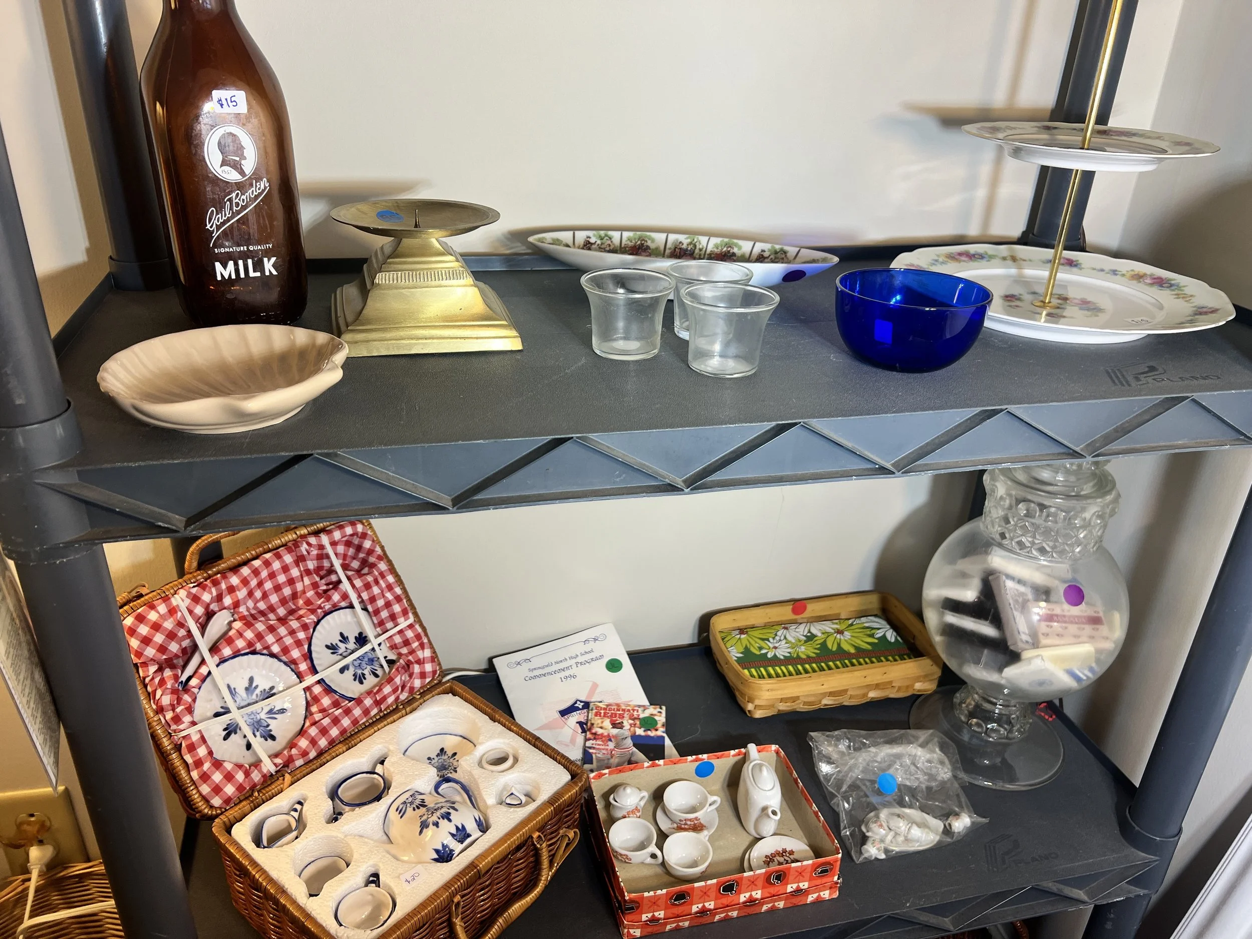 Miniature Porcelain & Glass – A set of blue and white miniature tea sets in a wicker picnic basket, shown with vintage Borden’s milk bottles and cobalt blue glassware