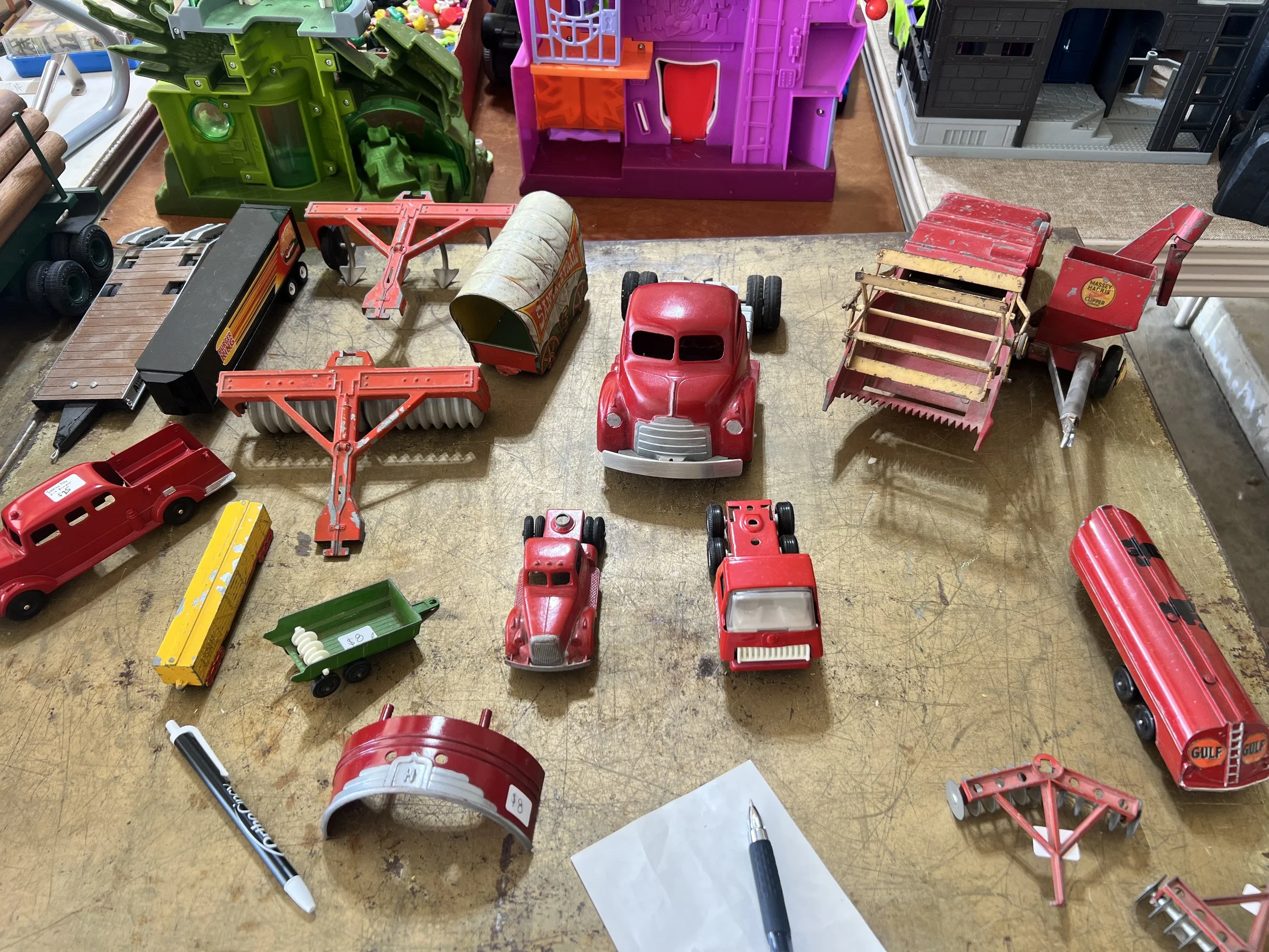 A collection of vintage red tractors, harvesters, and a Gulf Oil tanker, featuring Massey-Harris and Gulf branding