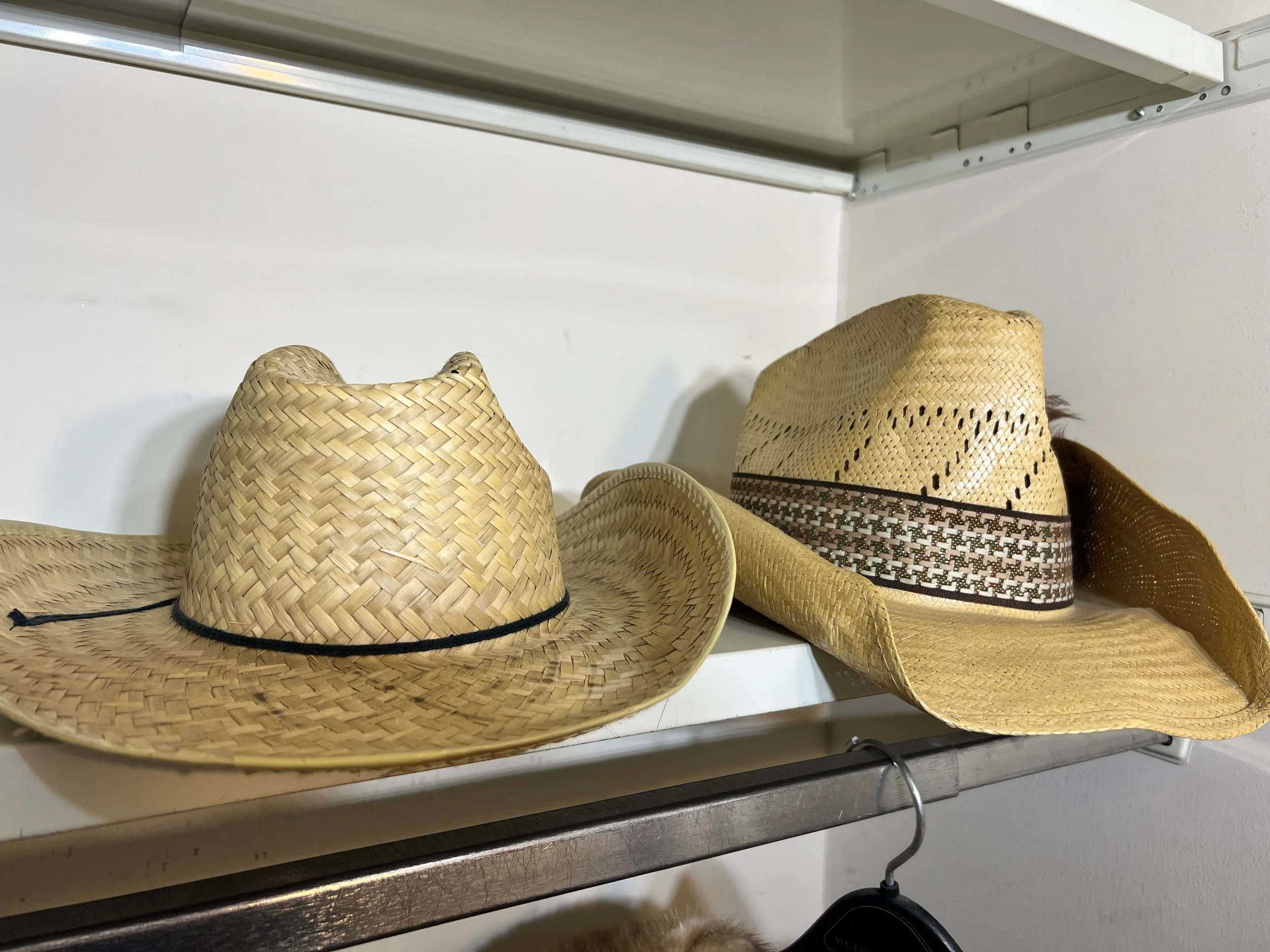A pair of classic woven straw cowboy hats, one featuring a decorative patterned band