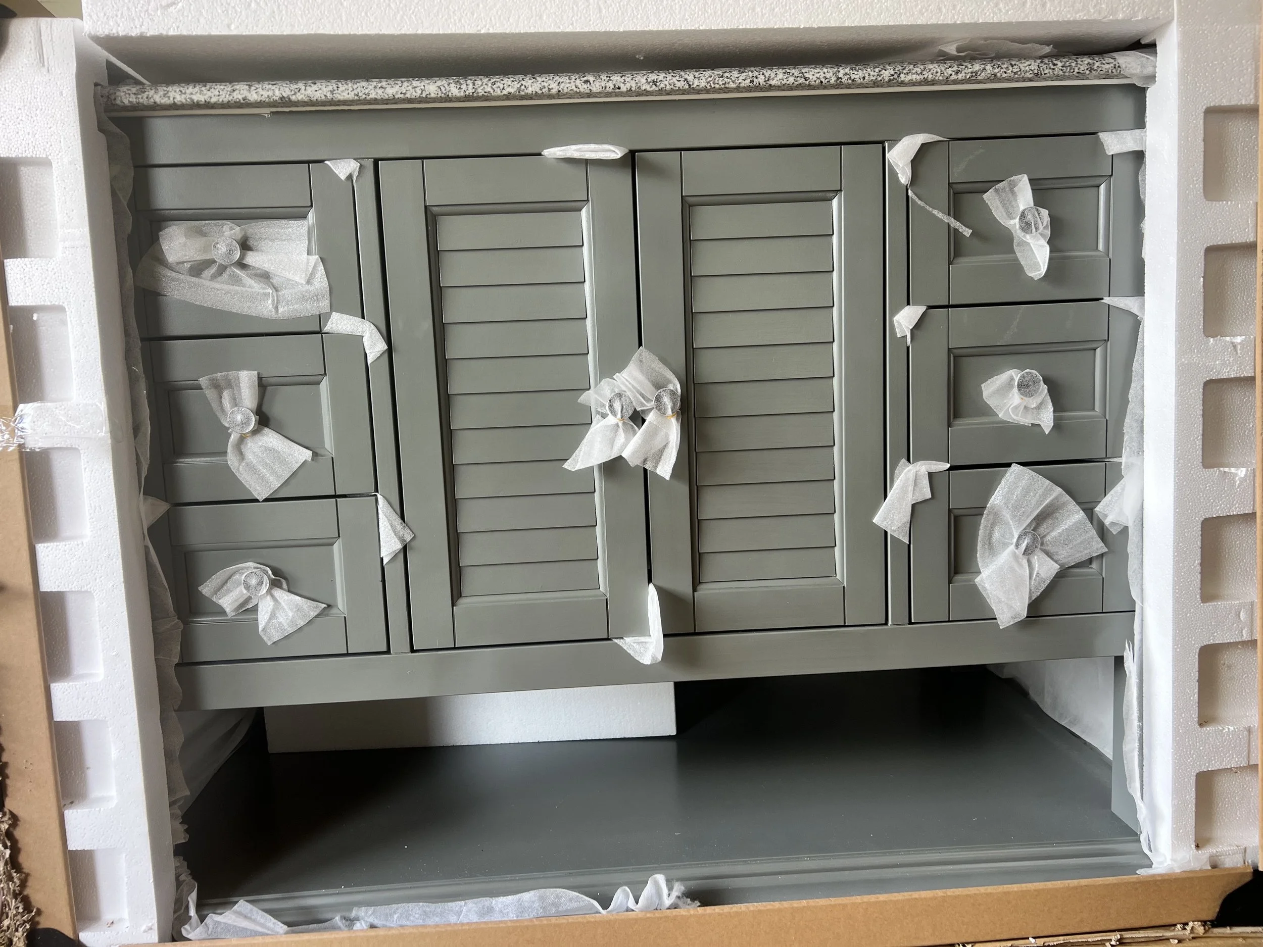 Grey Hamilton bath vanity with granite top, shown partially uncrated