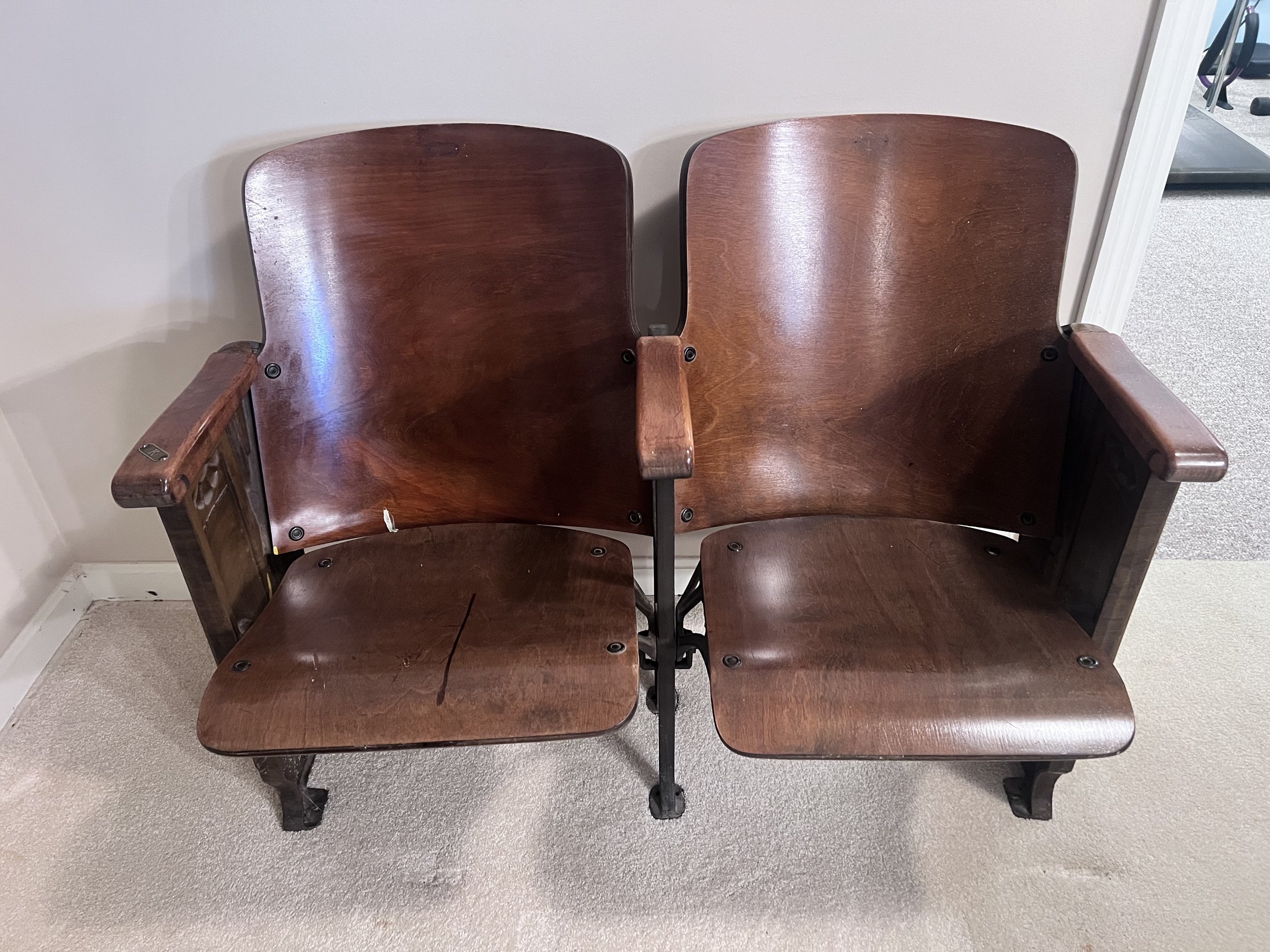Wooden double-seat theater bench featuring ornate Art Deco metal end panels