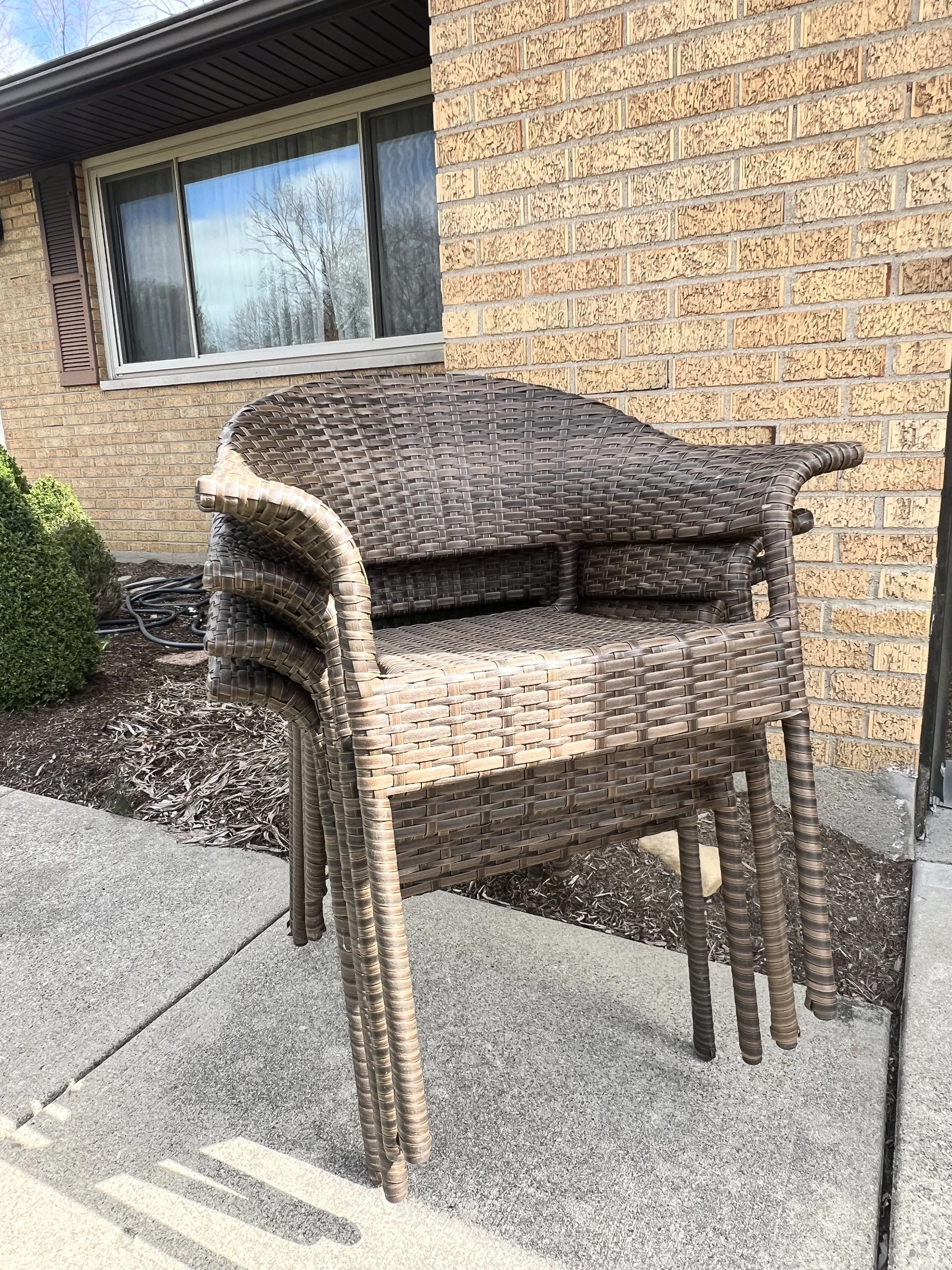 Stack of dark brown resin-wicker all-weather patio armchairs