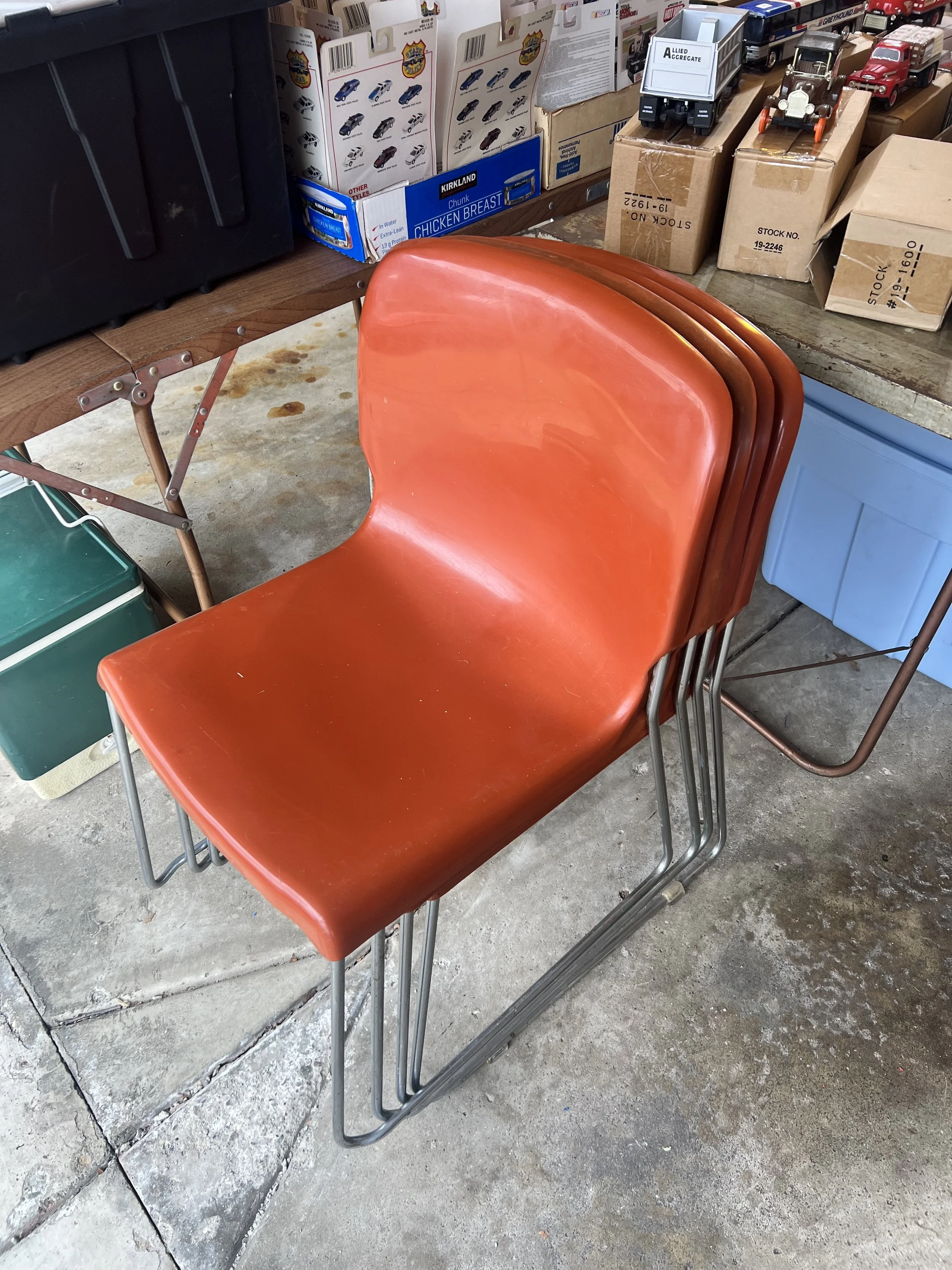 Four vintage orange molded shell chairs with chrome sled bases, perfect for a retro dining or office setup